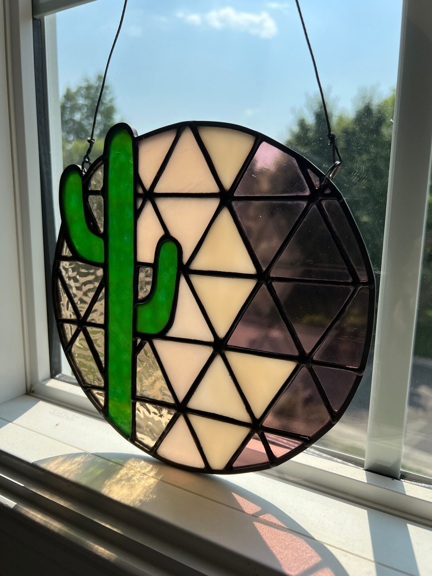 Colorful stained glass window with geometric shapes and a green snake design, seen through a glass window.