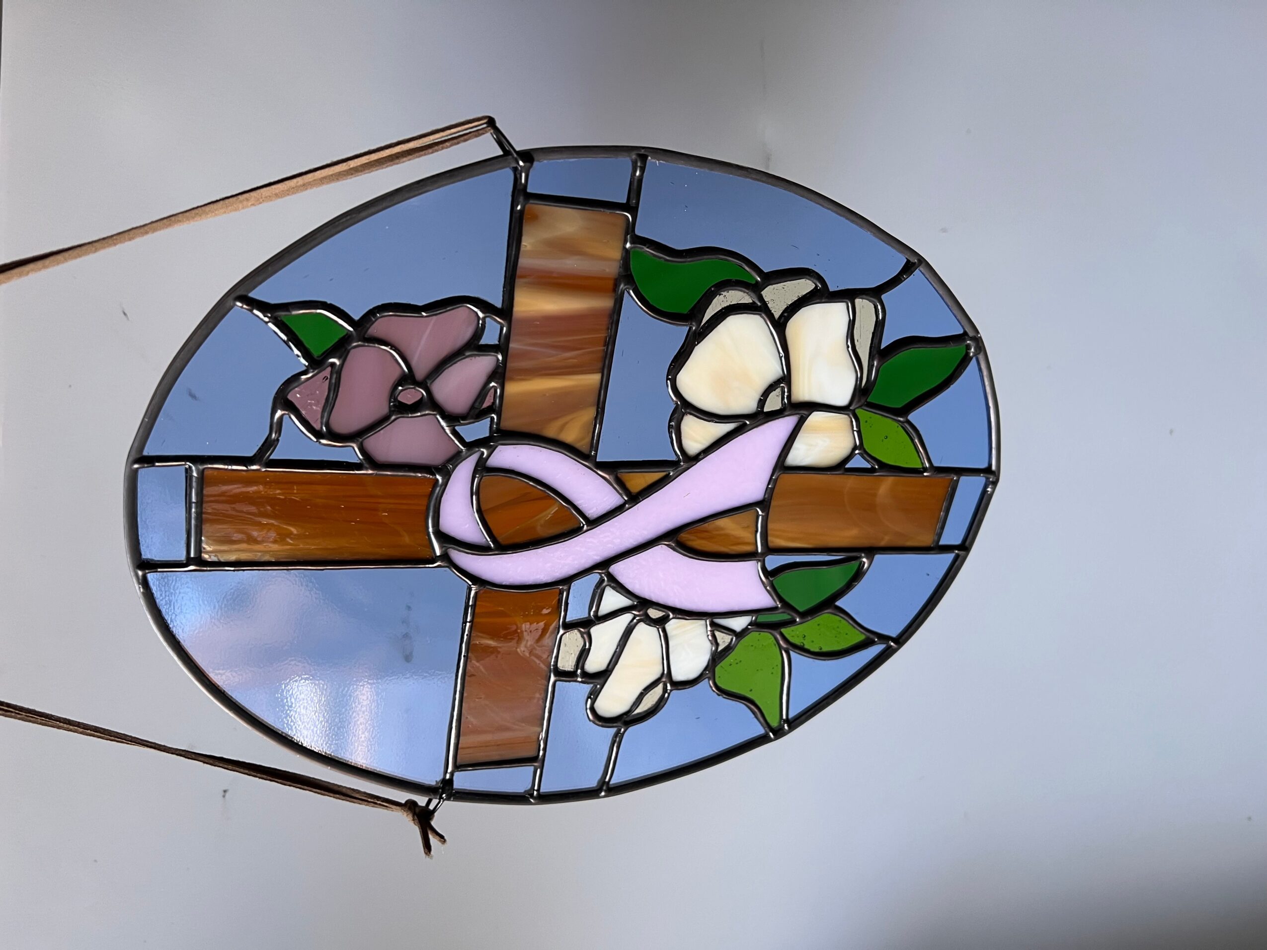 Colorful stained glass cross with flowers, set against a light background.