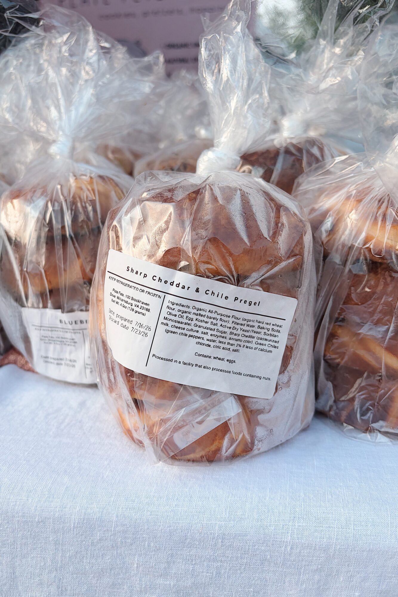 Three wrapped baked goods in clear plastic bags with labels, placed on a white surface.