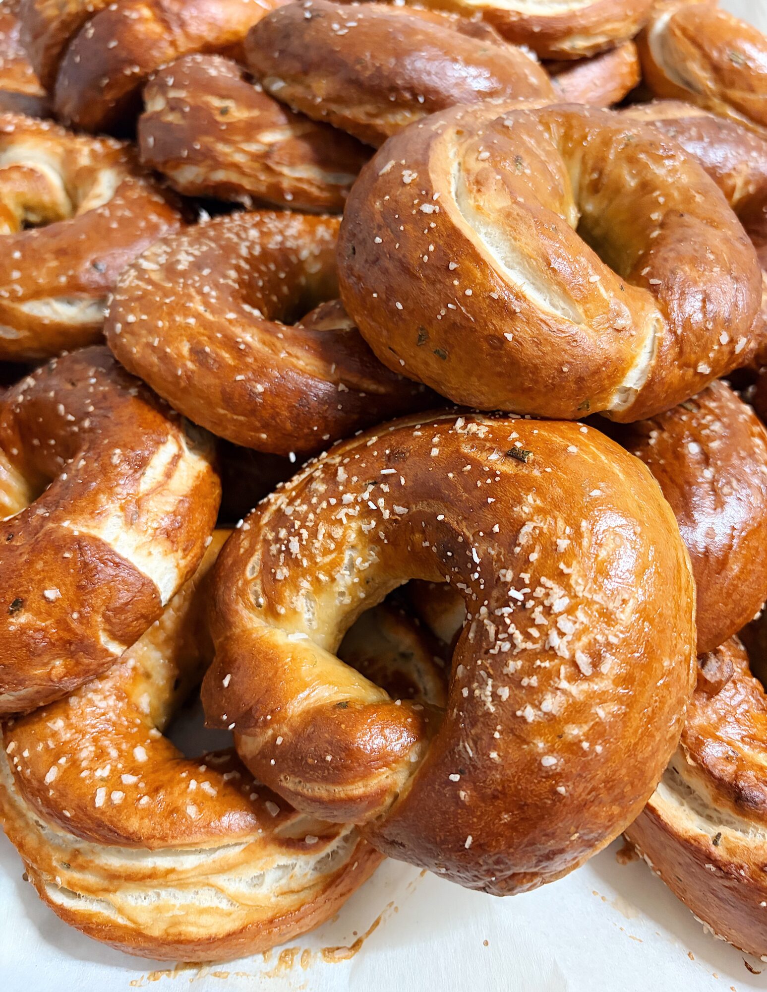 Close-up of glazed, salted pretzels piled together, showing shiny surface and salt crystals.