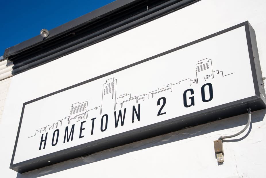 Sign with city skyline outline and text 'HOMETOWN 2 GO' on a white background.