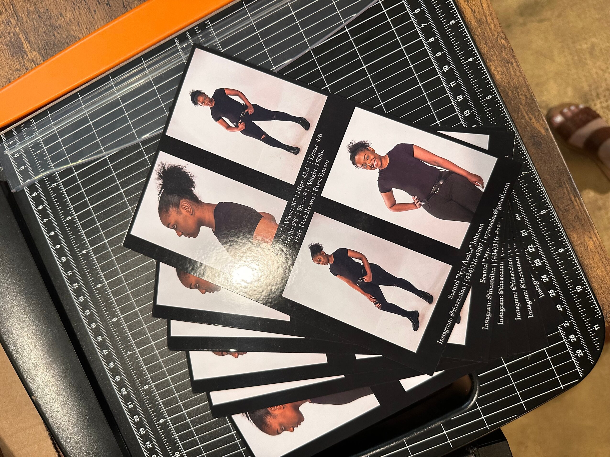 Six printed photographs of a person with curly hair and dark clothing are scattered on a cutting mat.