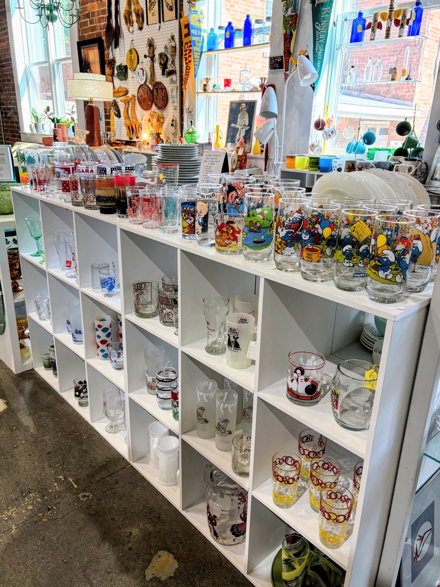White shelving unit with glass jars filled with colorful candies and small toys, in a bright store interior.