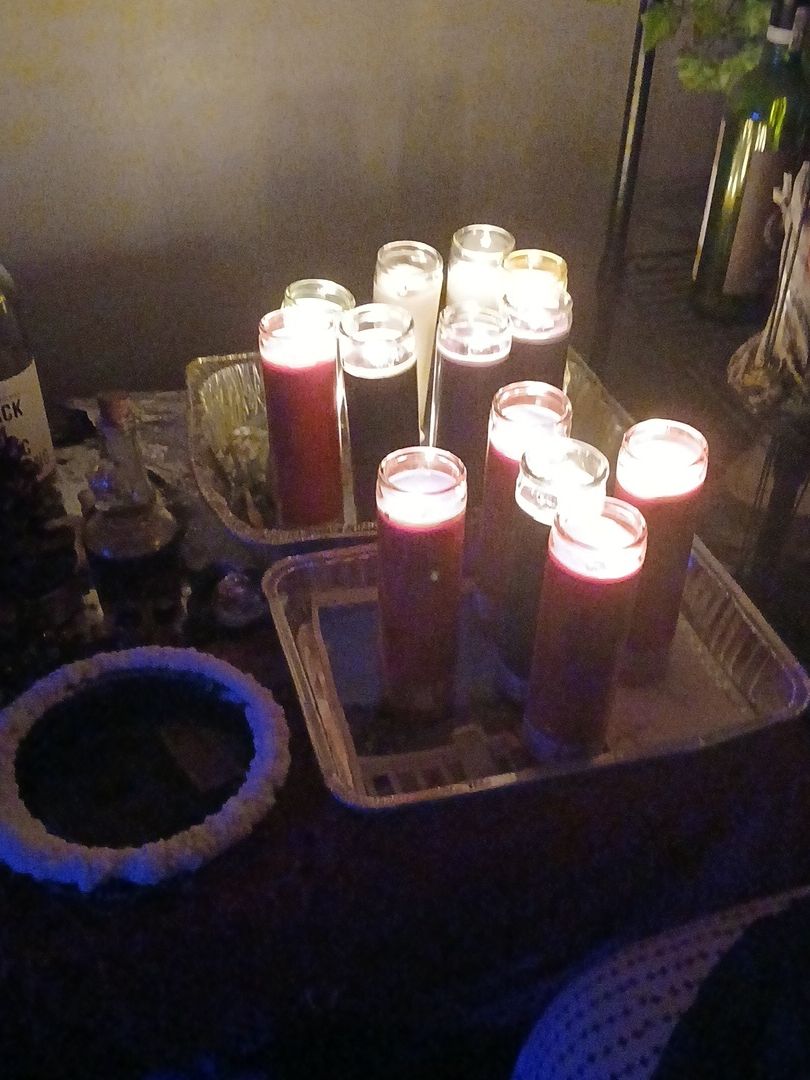 A tray with lit candles and a red cup on a table, with a dark background.