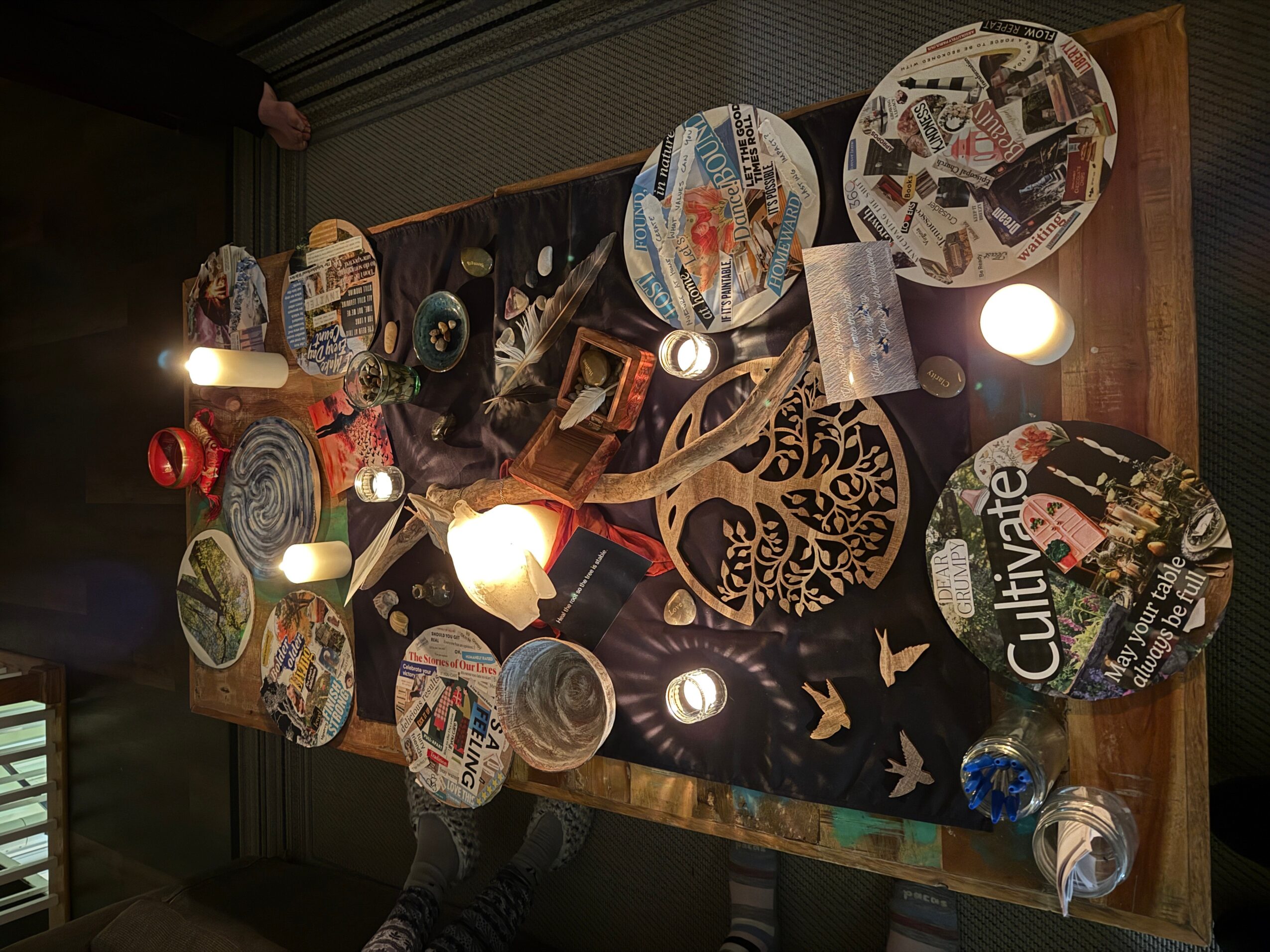Table with various plates, glasses, and decorative items, viewed from above, with a dark background and some light reflections.