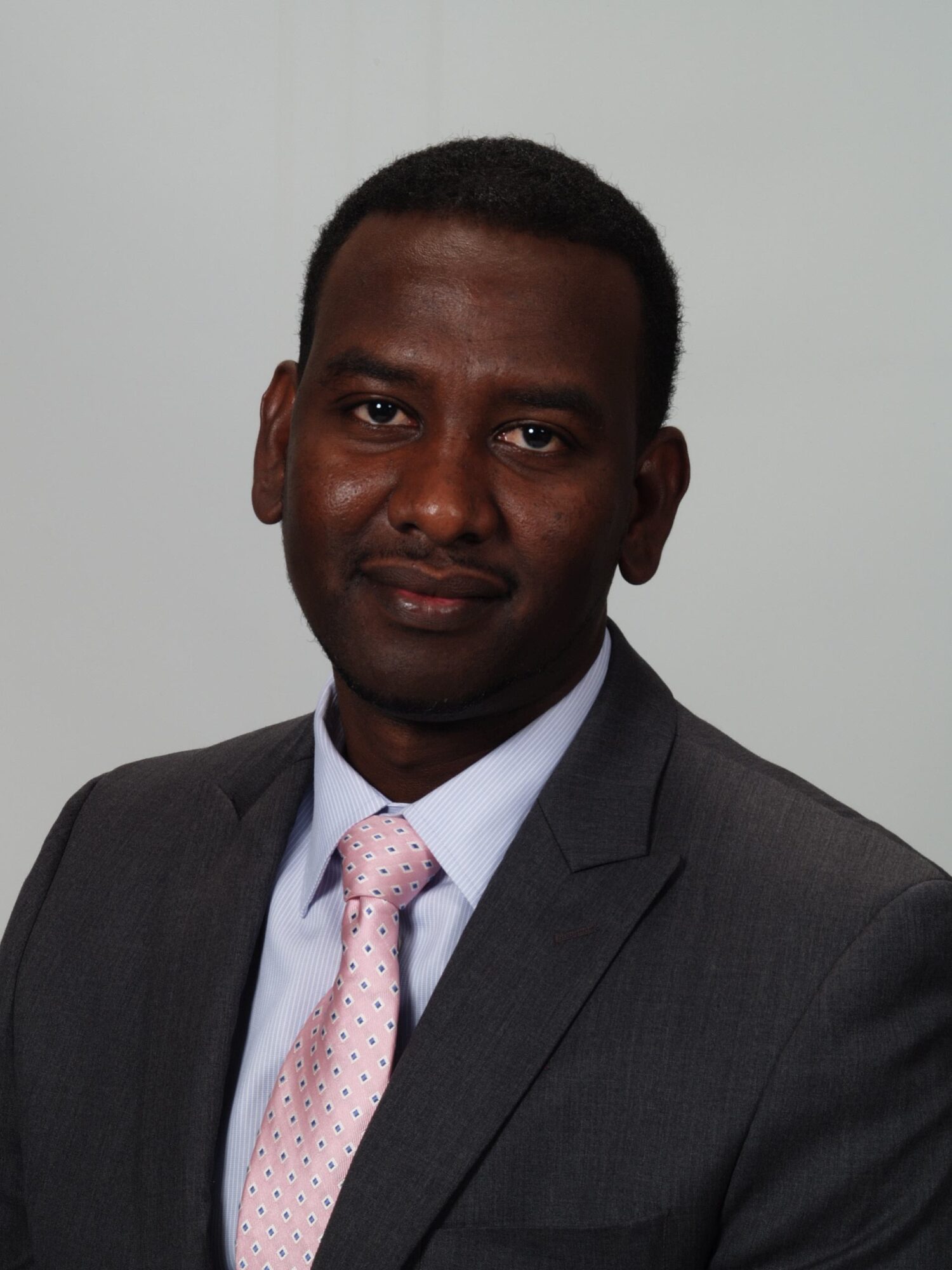 Portrait of a man in a suit and tie, facing forward, with a neutral background.