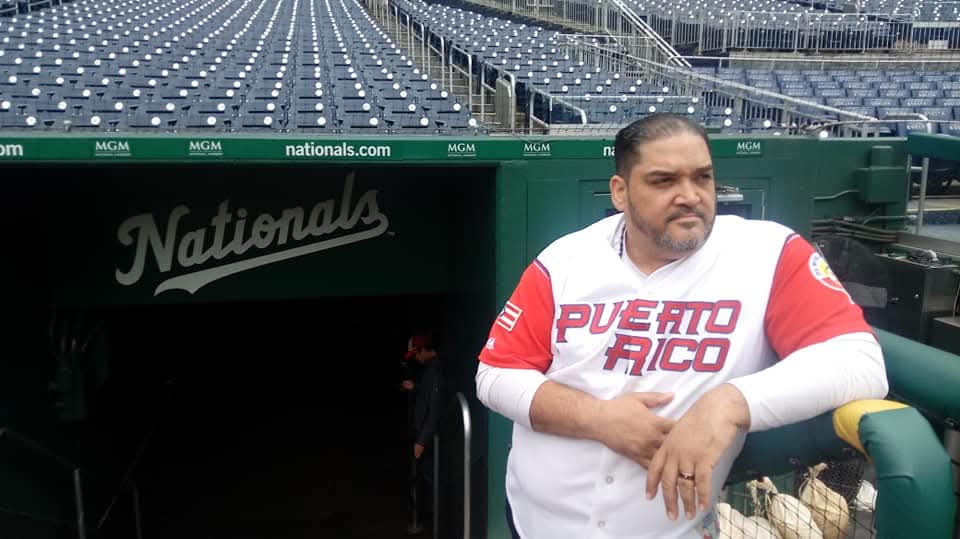 Man standing near stadium entrance with empty seats in background.