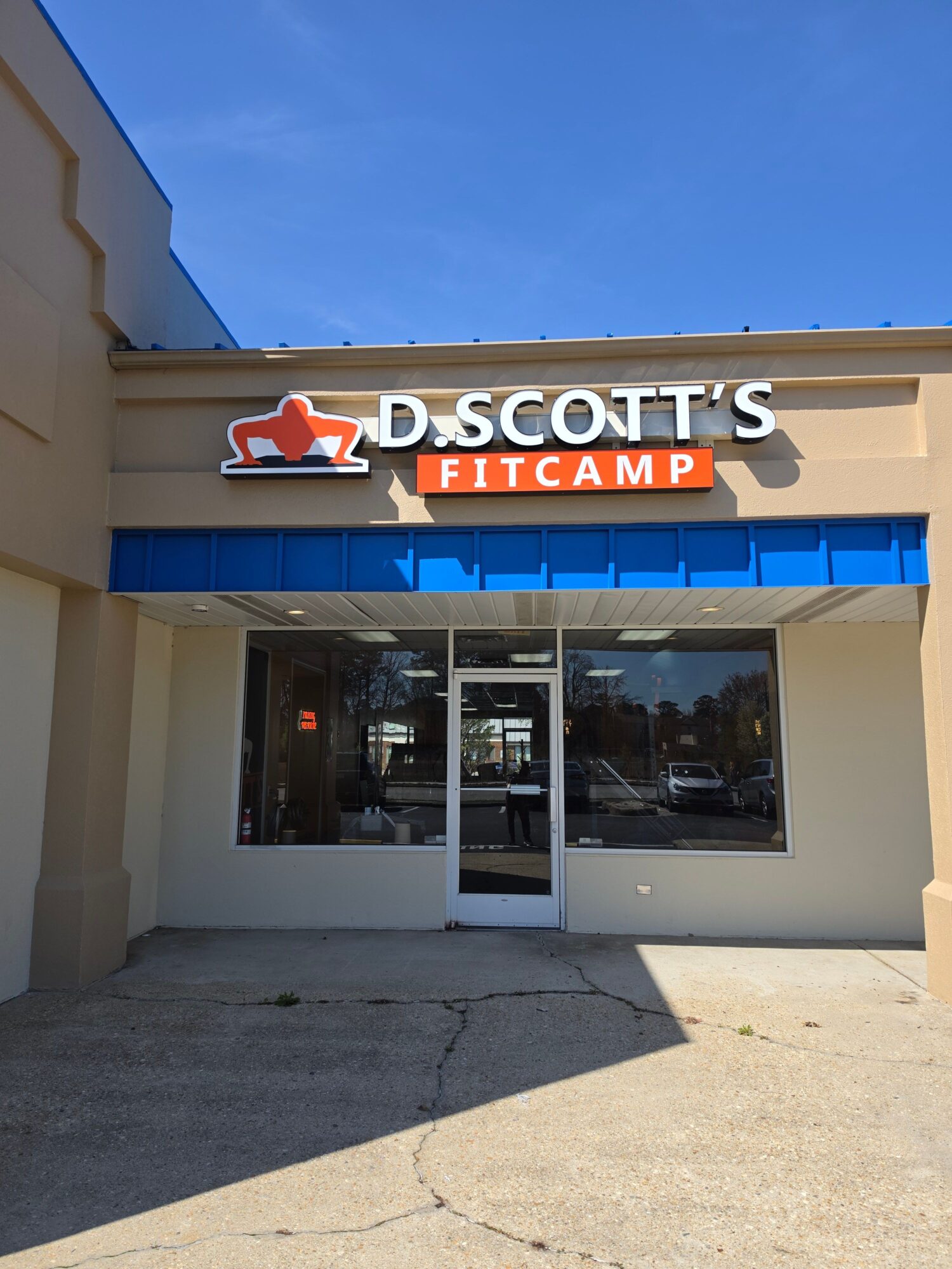 Football camp storefront with glass door and window, blue awning, and sign reading 'SCOTTS FOOTBALL CAMP' in red and white.