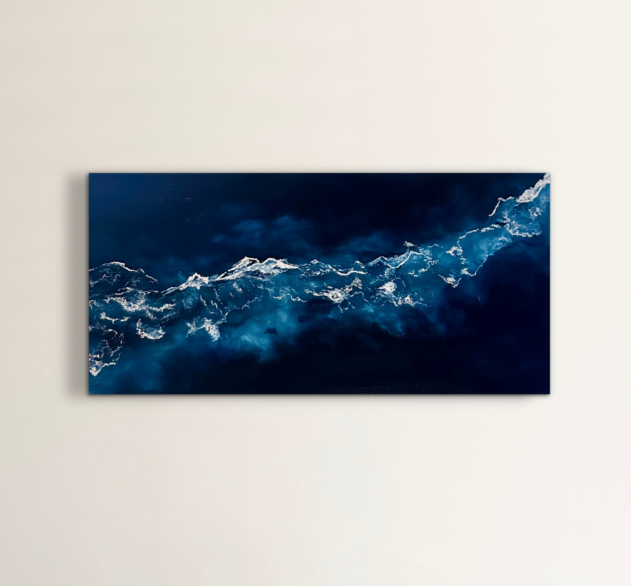 Abstract painting of ocean waves in dark blue and white, horizontal orientation, on a white wall.