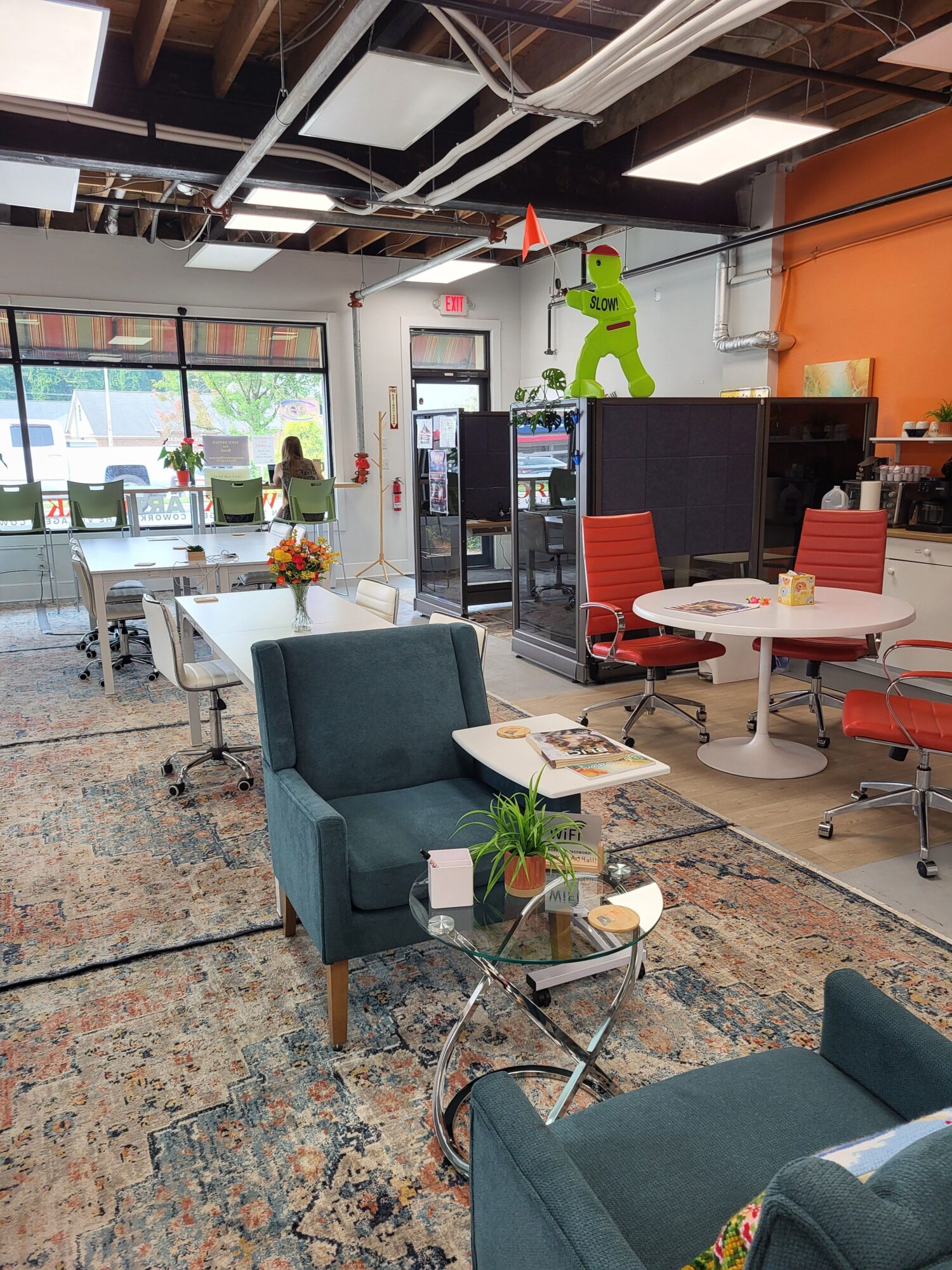 Office or lounge area with chairs, tables, a TV, and a window with a view outside.