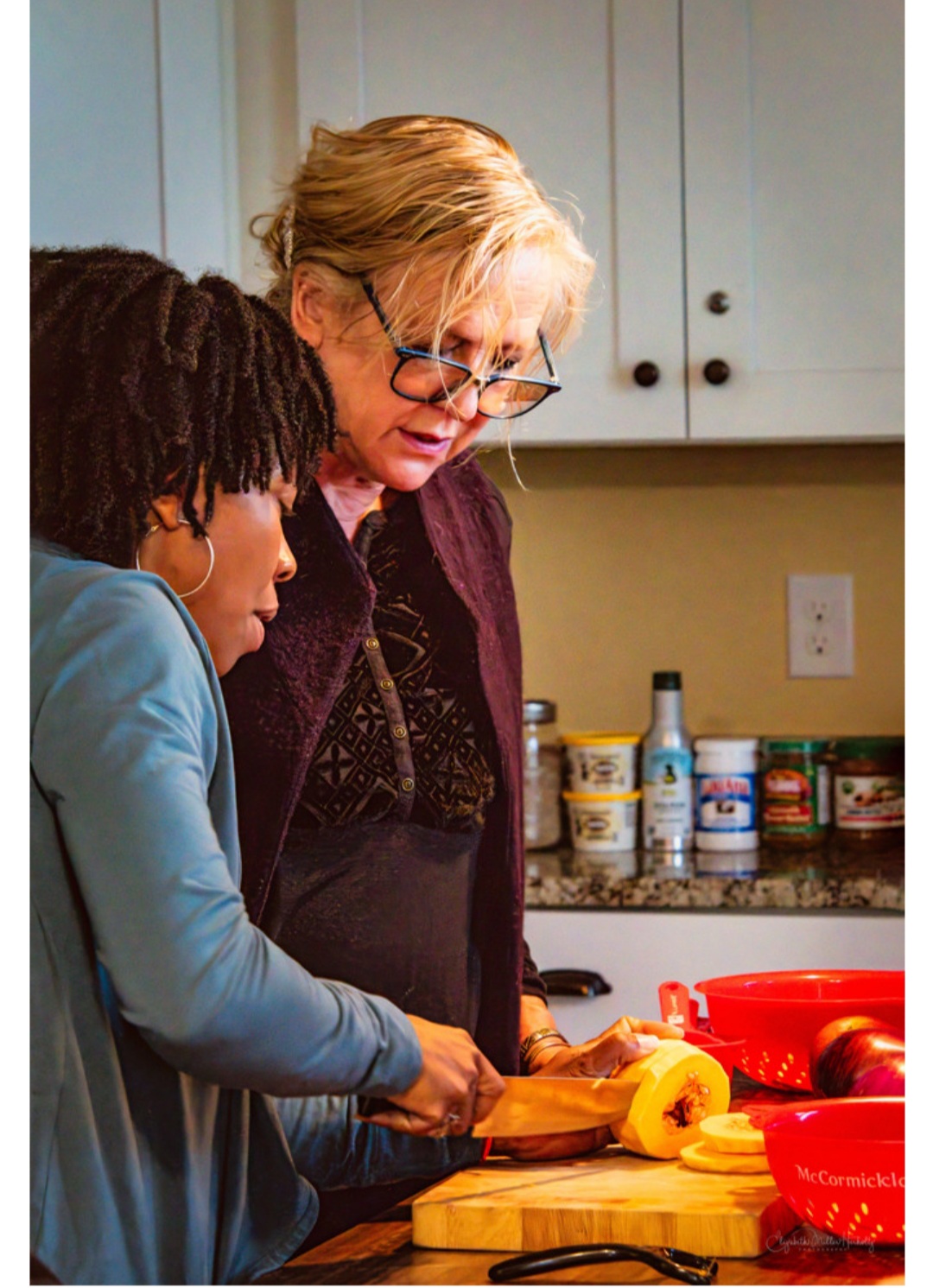 An elderly woman and a young girl prepare food together in a kitchen, focusing on a cutting task.