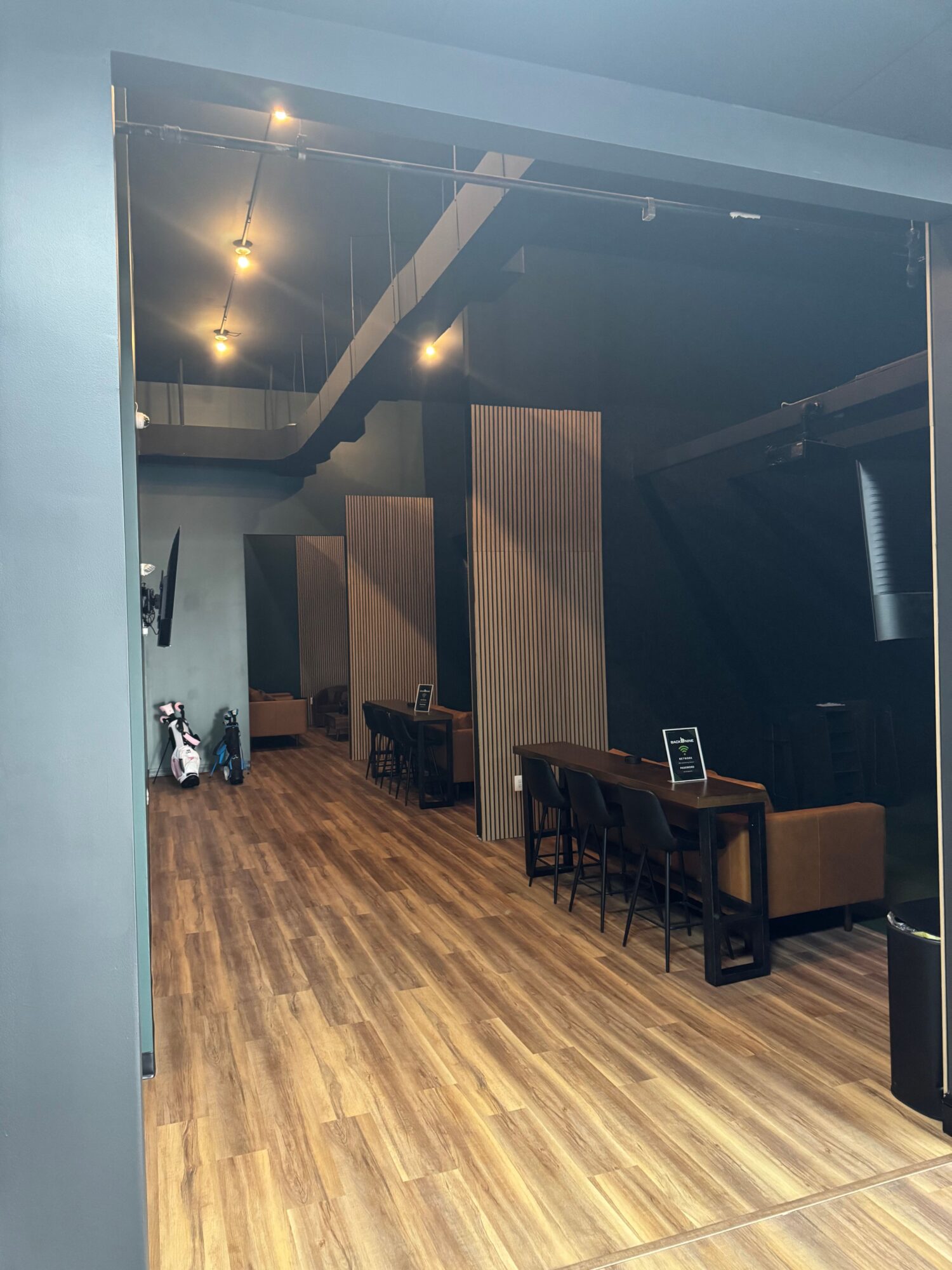 Interior of a room with wooden flooring, black furniture, and a wooden partition, viewed from the side.