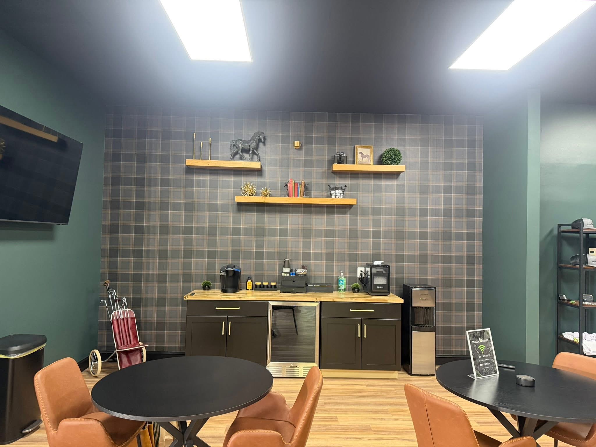 Kitchen area with black and yellow cabinets, two shelves with decorative items, and a plaid wall background.