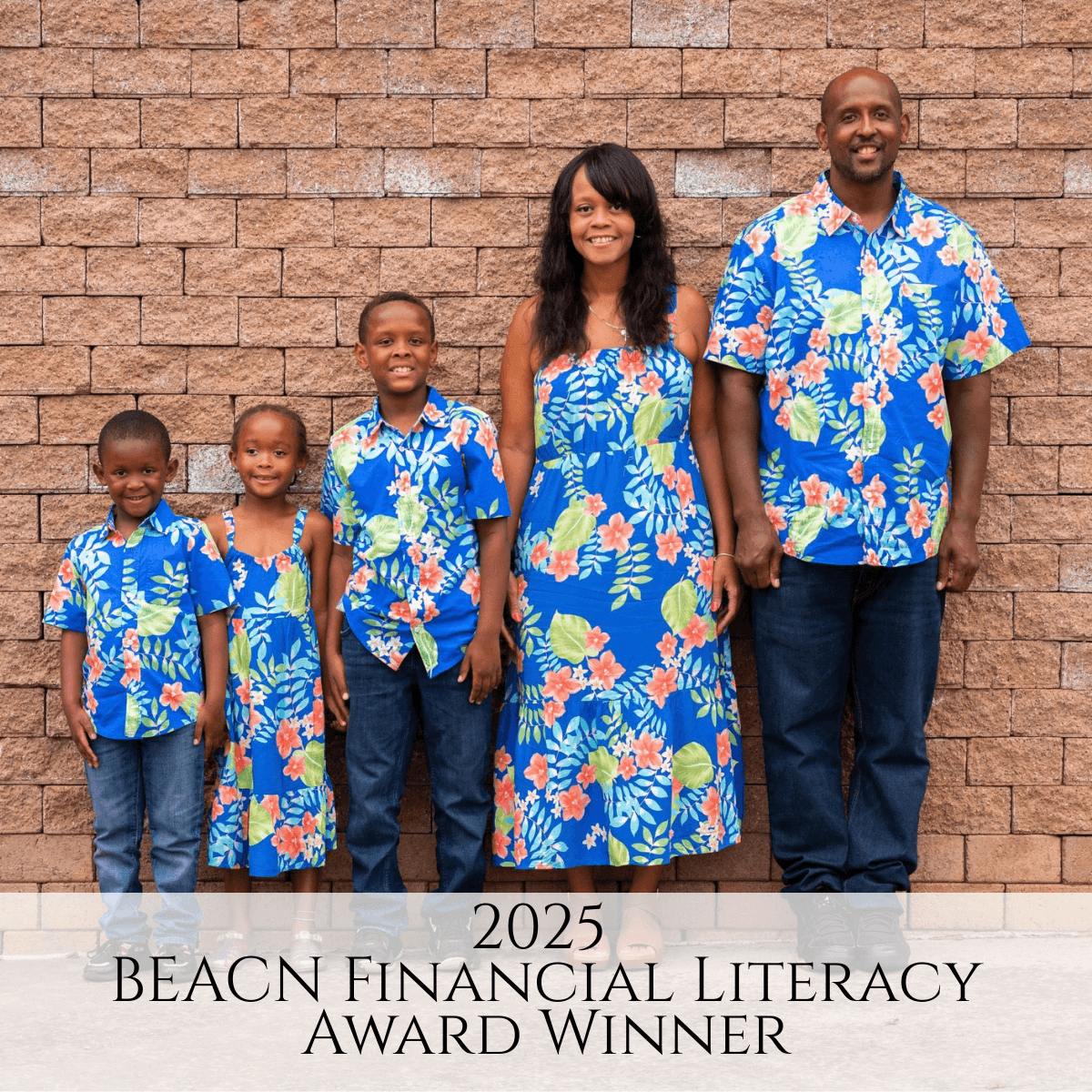 Family of five standing against a brick wall, all wearing matching blue floral outfits, smiling.