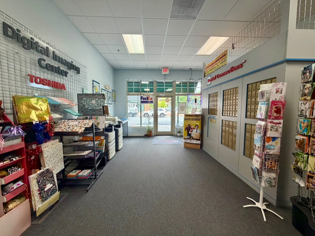 Indoor hallway with display shelves, a door at the end, and signs on the walls, including 'Digital Imaging Center'.