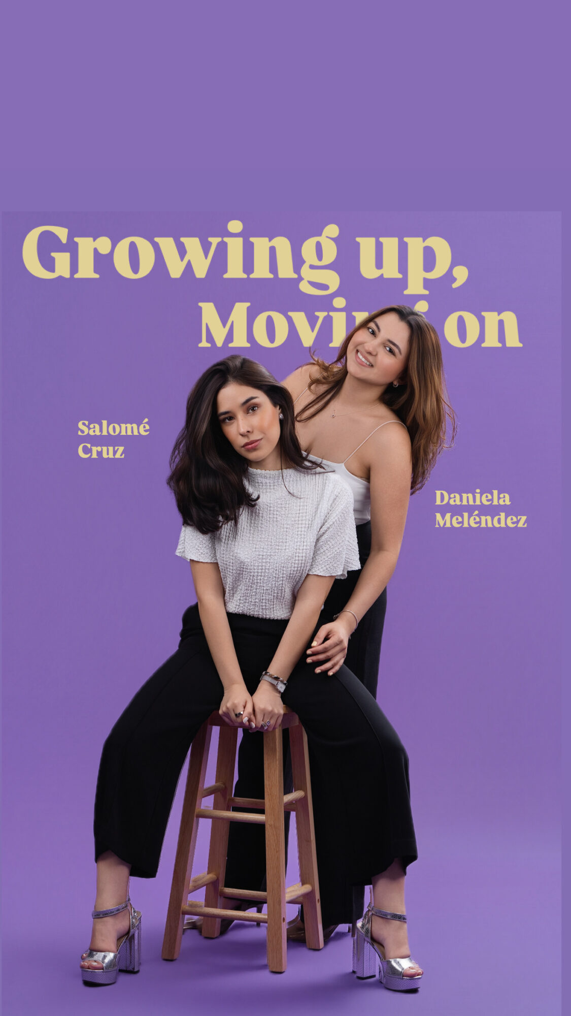 Two women pose with one sitting on a stool and the other standing behind, against a purple background with text.