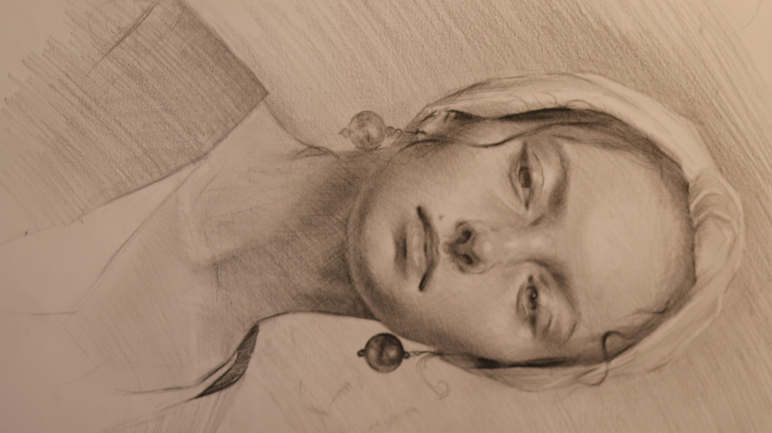 Portrait of a woman with long hair, lying on a wooden surface, looking at the camera, in sepia tone.