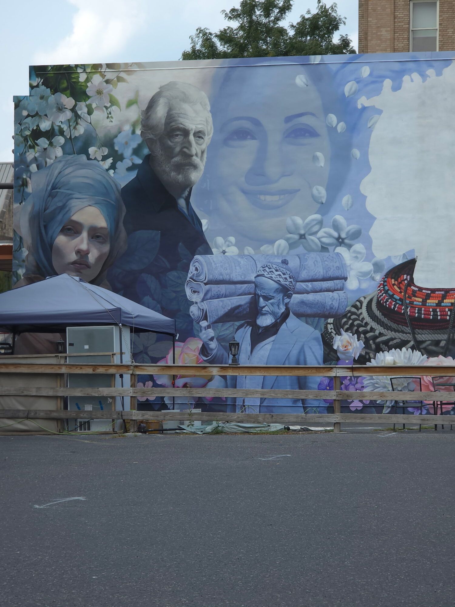 Colorful mural featuring portraits of a man, a woman, and a smiling face, with floral and cultural elements.