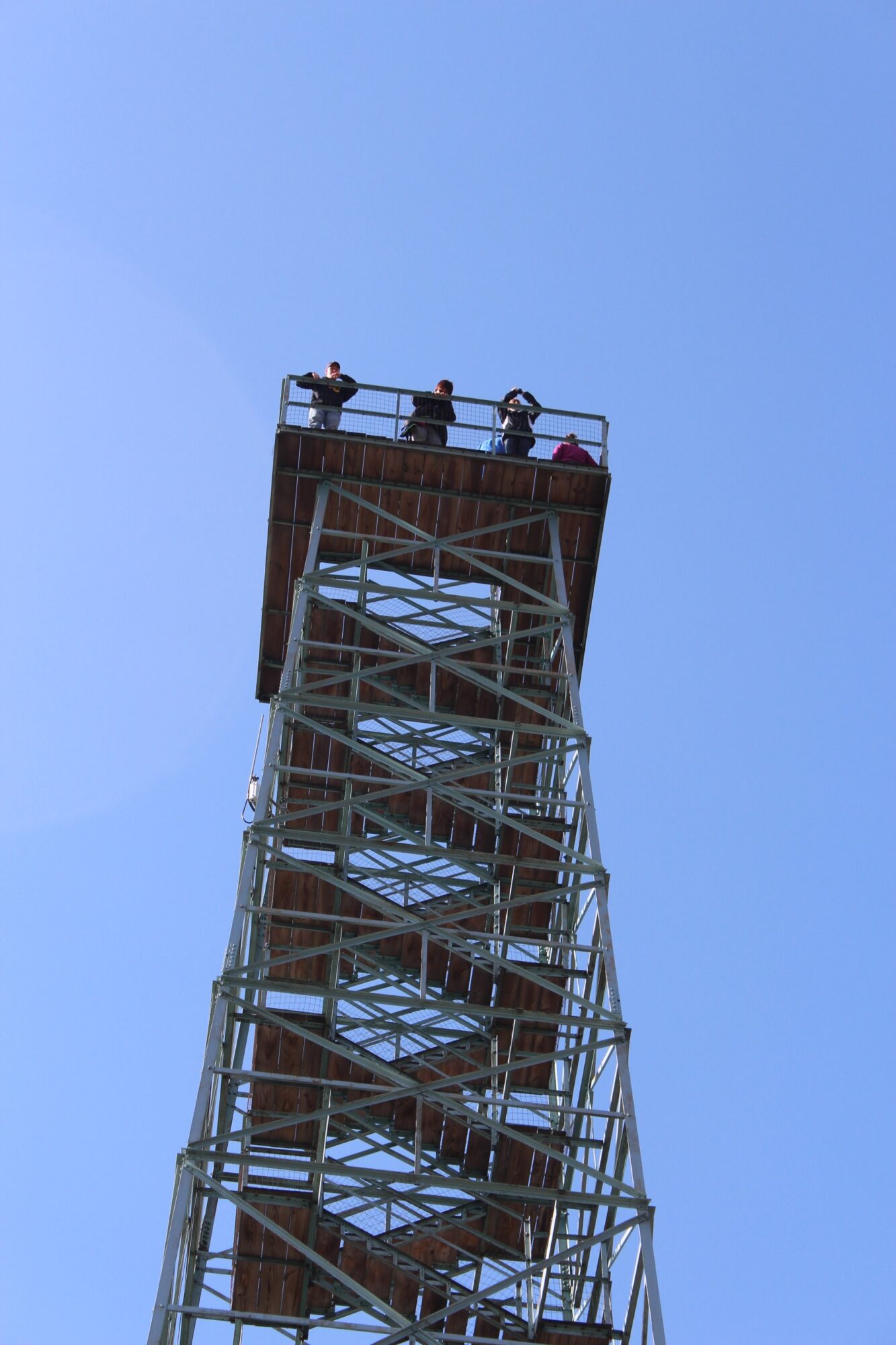 View of a tall metal tower with a platform at the top, against a clear blue sky.