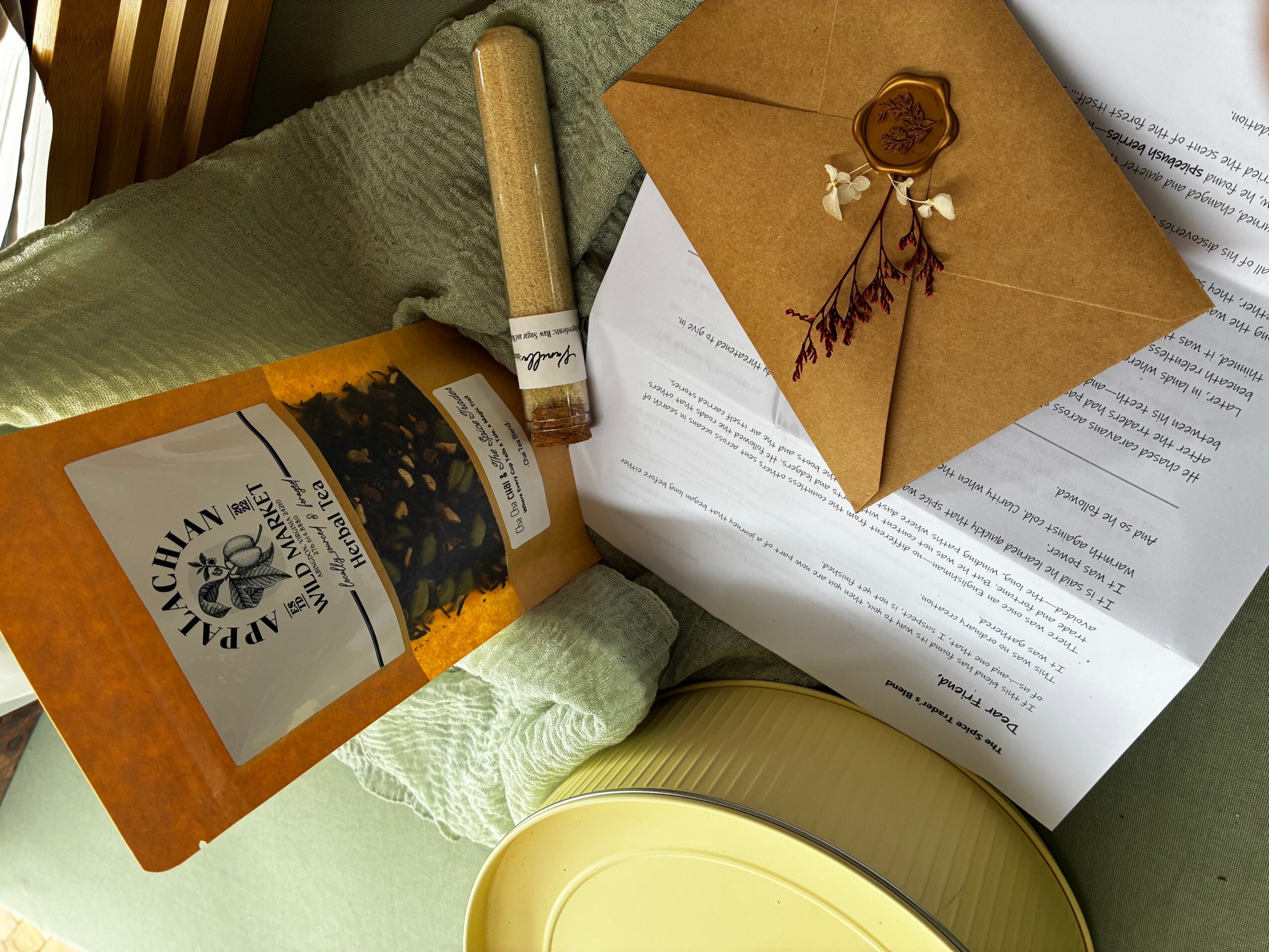 A sealed bag of tea, a rolled paper, an envelope with a wax seal, and a document on a green surface.