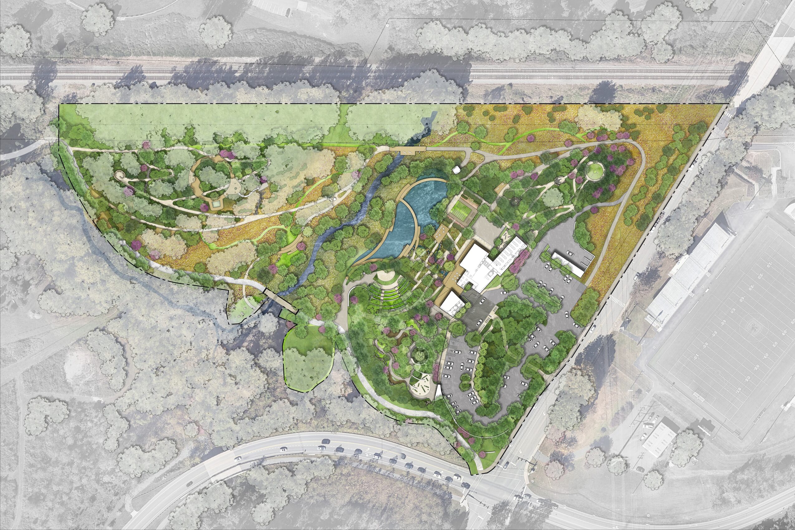 A landscaped park with pathways, water features, and green areas, surrounded by roads and buildings, viewed from above.
