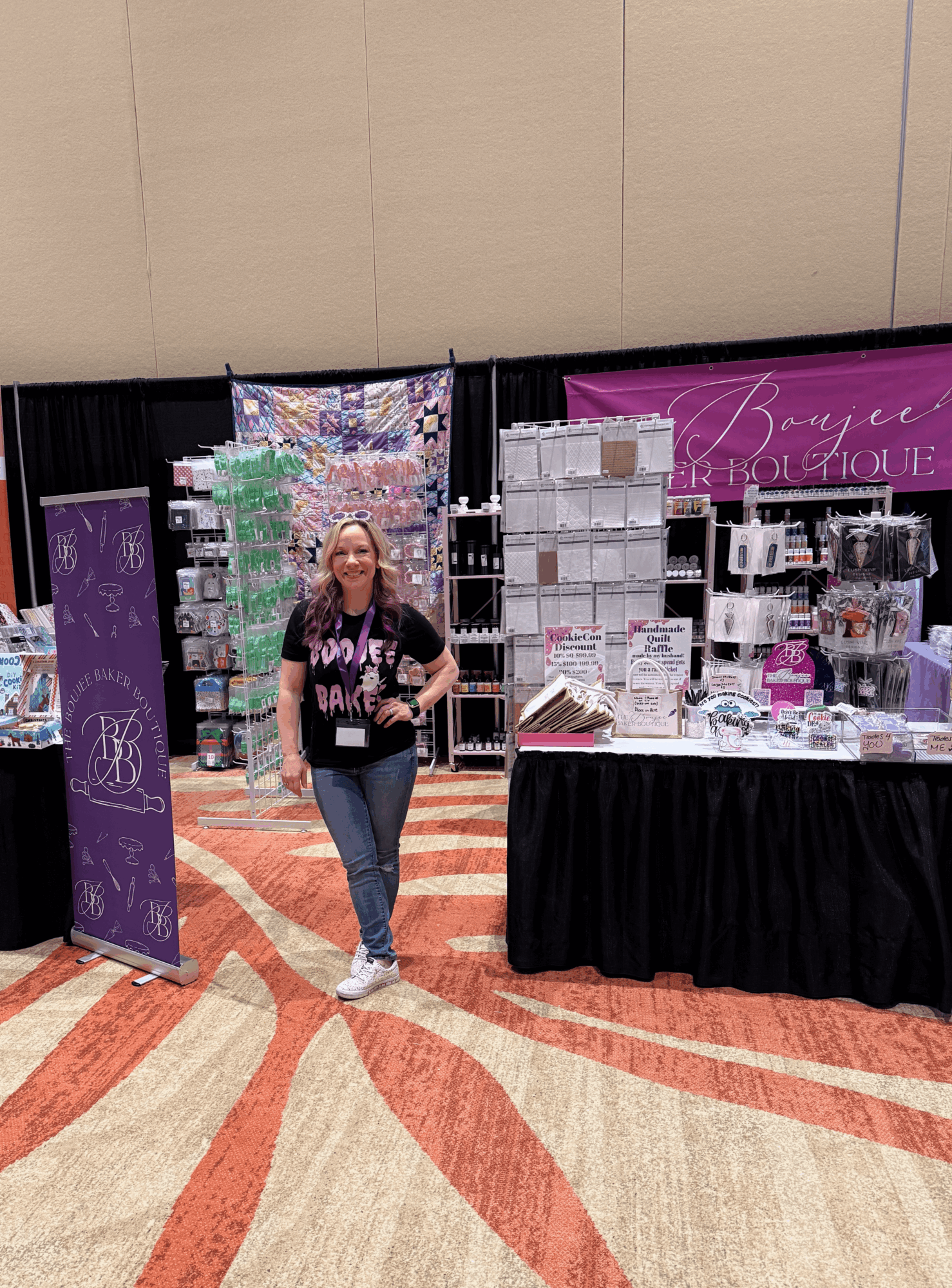 Woman standing in front of a booth with beauty products and displays at an indoor event.