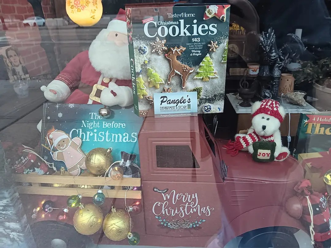 Display of Christmas-themed items including cookies, ornaments, a plush Santa, and a plush snowman, with festive packaging and decorations.