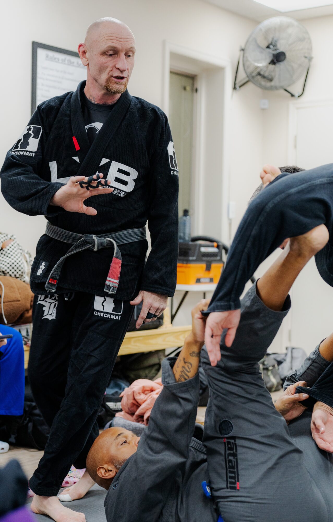 Instructor demonstrating a technique to a person lying on the ground in a medical or training setting.