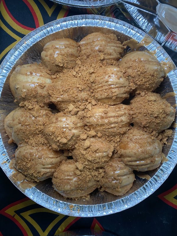 Tray of éclairs topped with crushed nuts or crumbs, arranged in a circular pattern.