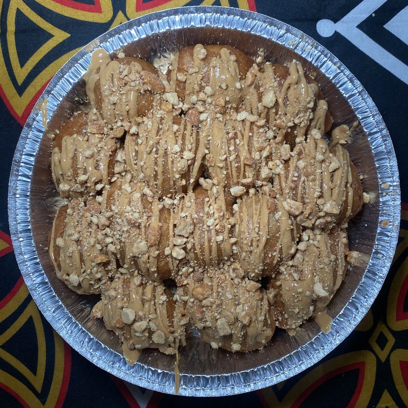 Tray of cookies topped with crushed nuts, arranged in a circular pattern, on a decorative surface.