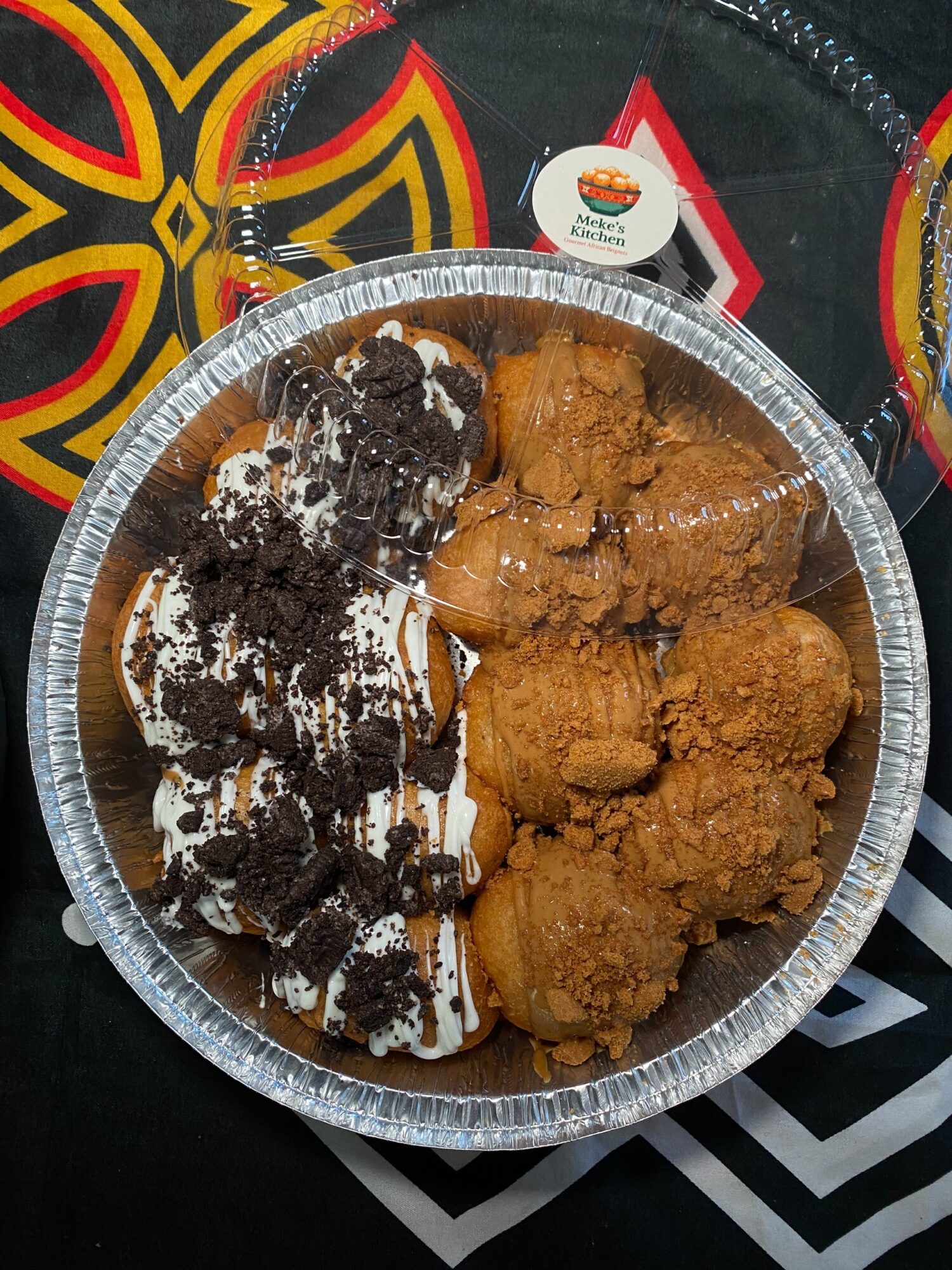 Aluminum tray with half chocolate and half fried chicken pieces, placed on a colorful patterned surface.