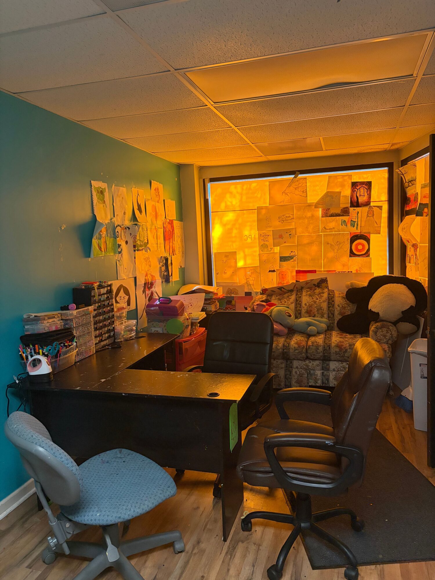 Office with chairs, a desk, and a window showing a colorful wall outside.