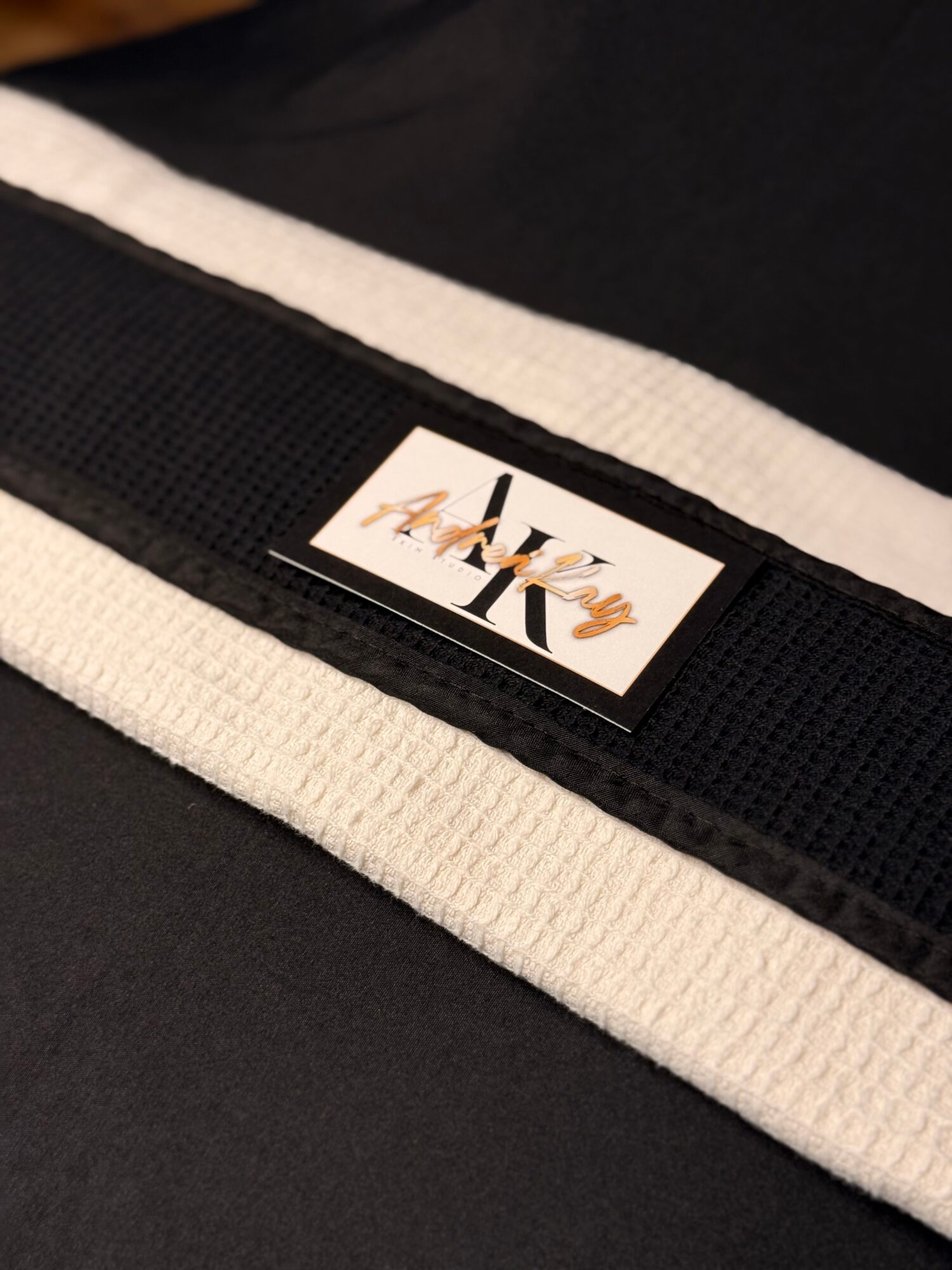 Close-up of a black and white fabric with a small label reading 'Alyce' attached to a black strap.