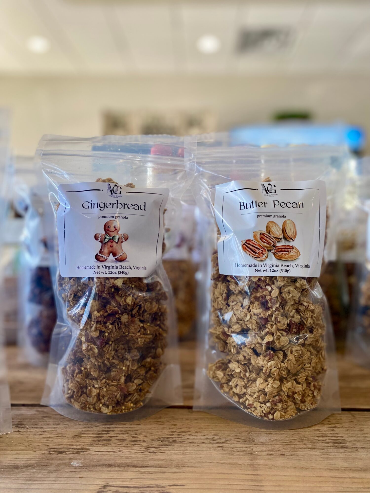 Two clear plastic bags of baked goods on a wooden surface, with labels reading 'Gingerbread' and 'Biscuit Pecan'.