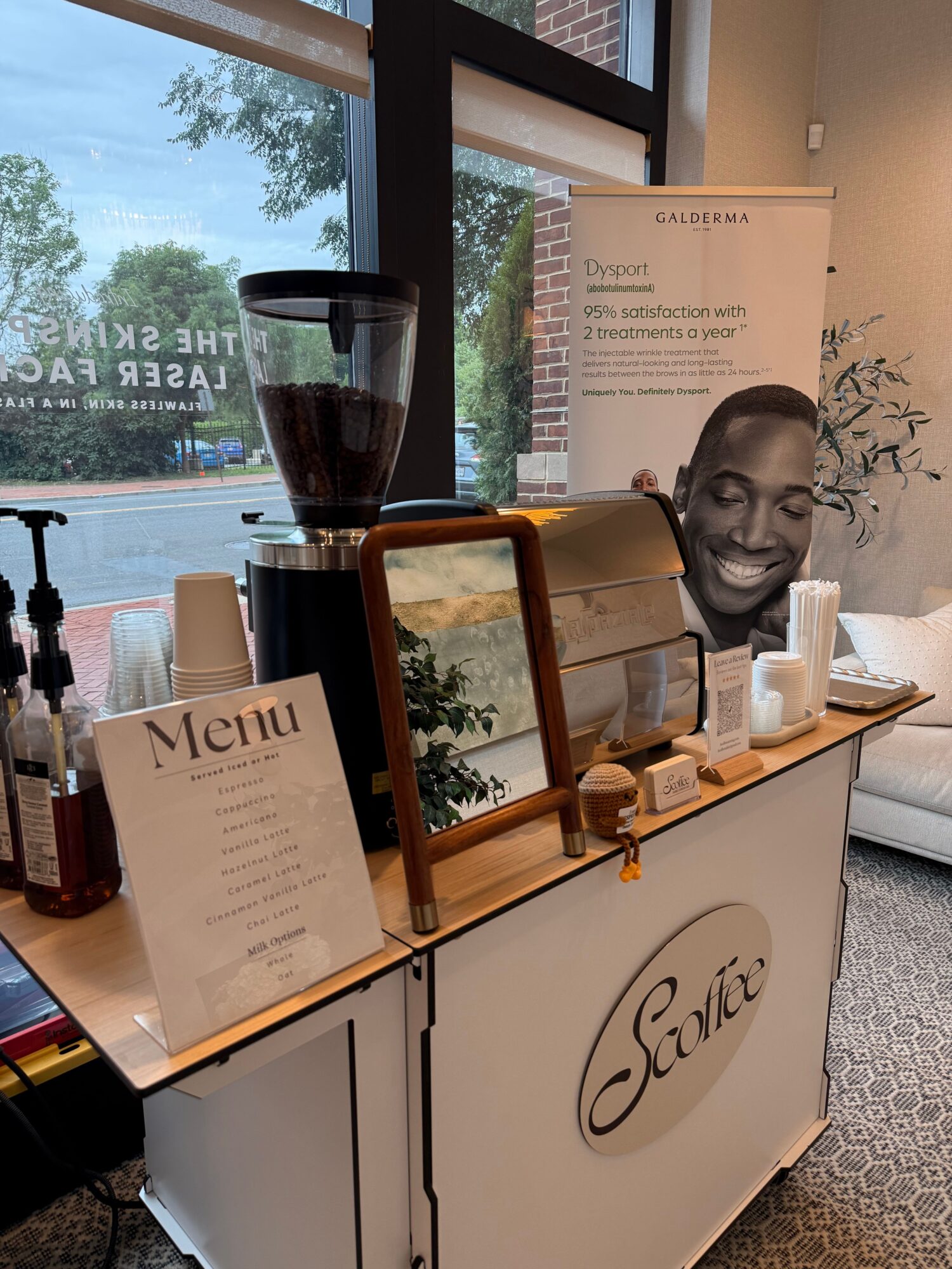 A display table with a mirror, a lamp, and a menu, with a poster and window in the background.