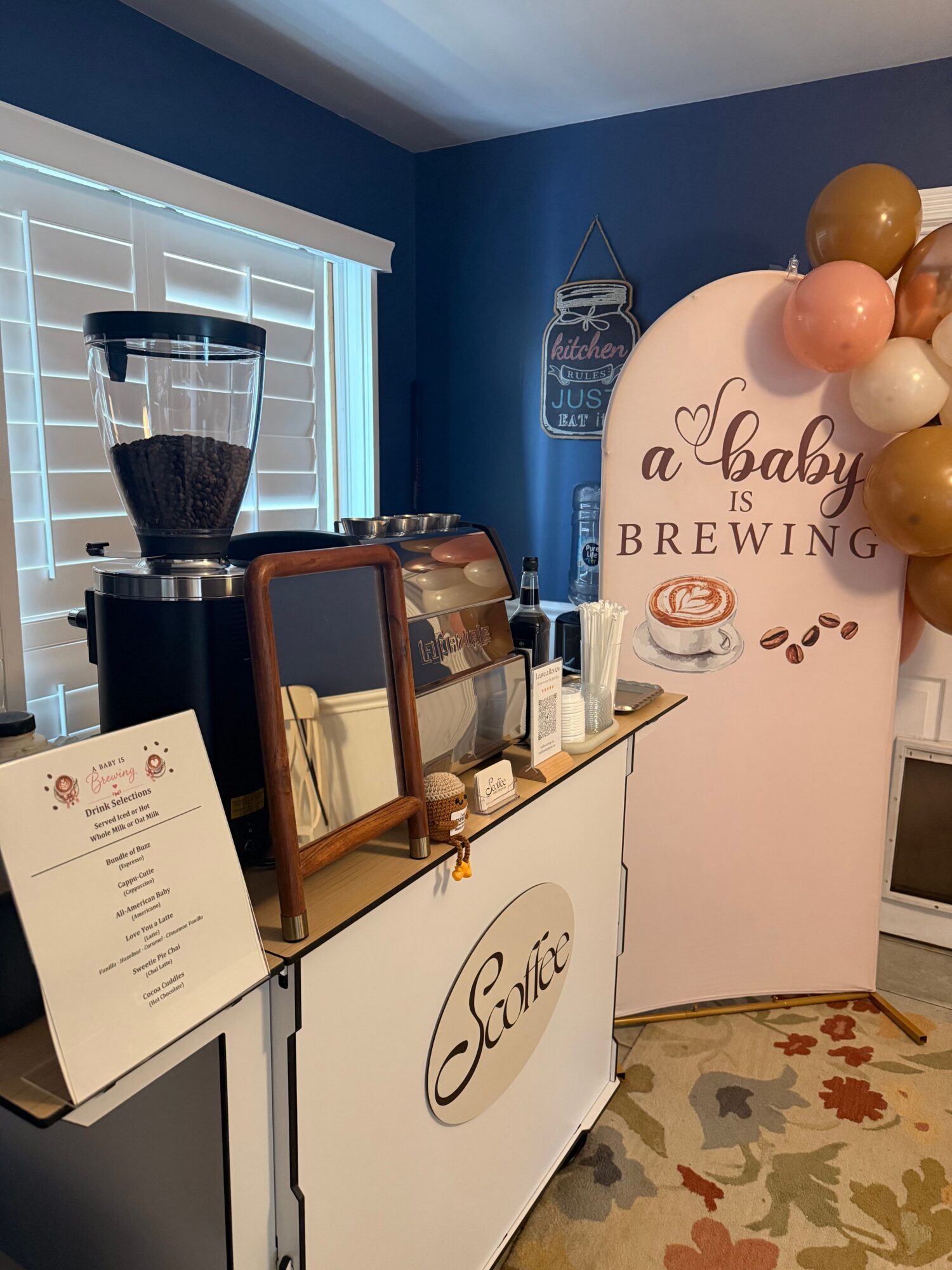 Table with a menu, a glass, and a black lamp, against a backdrop with balloons and a sign reading 'a toast to BREWING'.