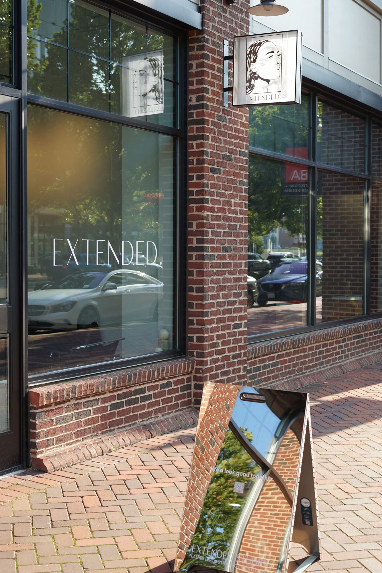 Brick building with large glass window and a sign that reads 'EXTENDED' inside.
