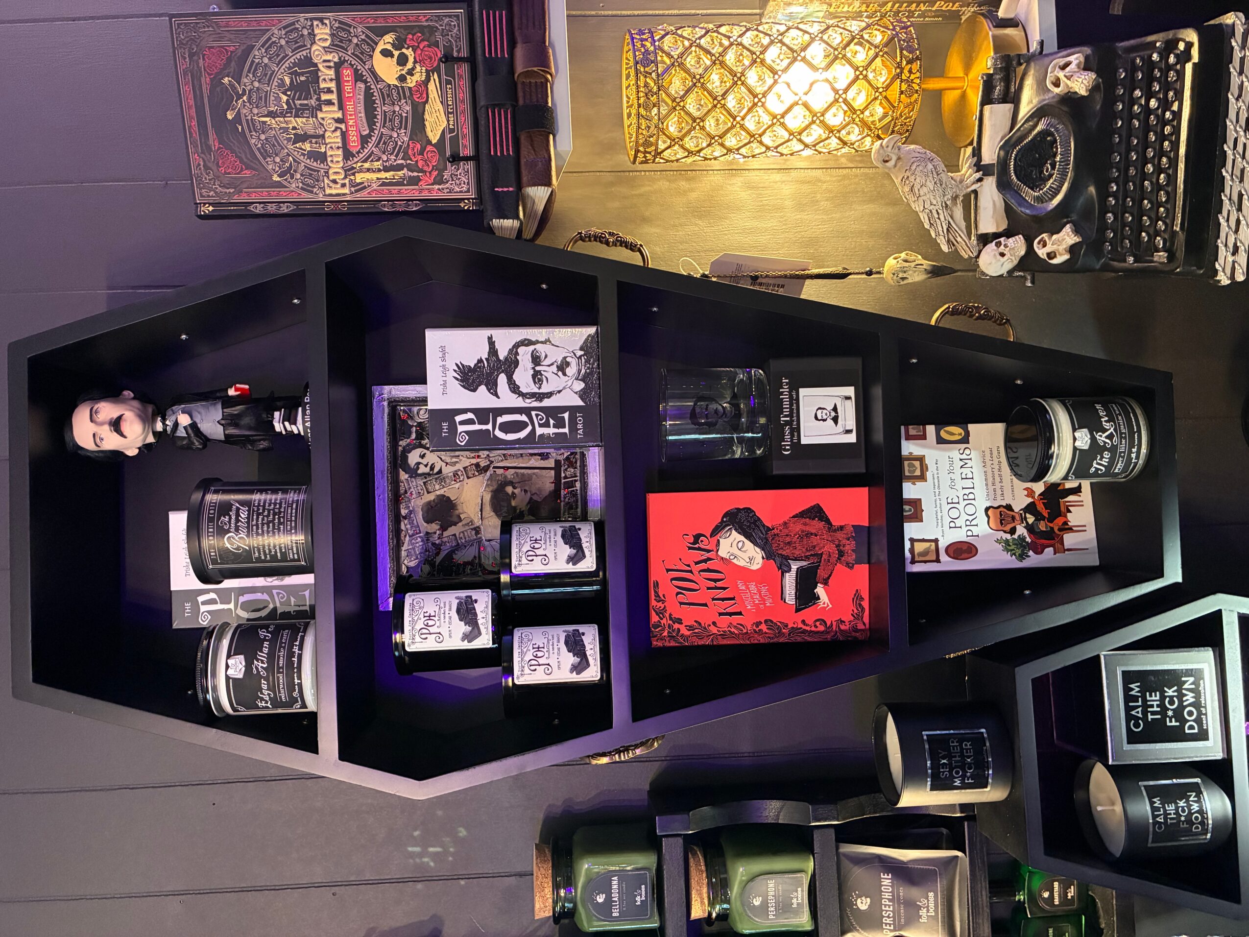 Black shelf with various decorative items, books, and framed pictures, with colorful objects and artwork in the background.