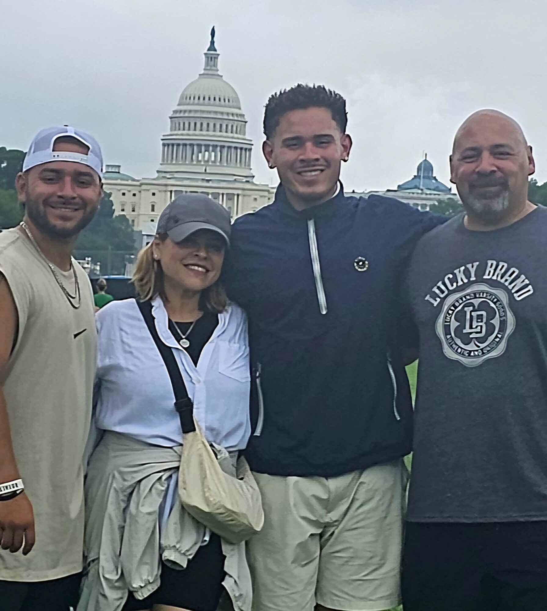 Four people standing outdoors with the U.S. Capitol building in the background, smiling at the camera.