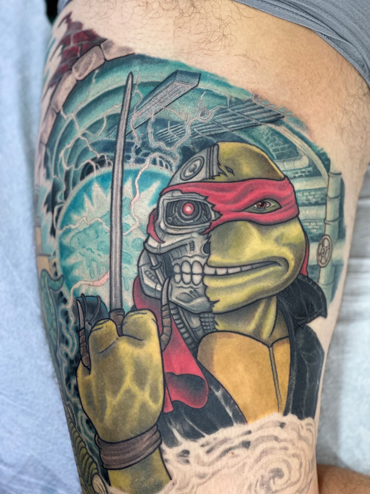 Tattoo of a Teenage Mutant Ninja Turtle with a robotic face, holding a weapon, with a futuristic background.