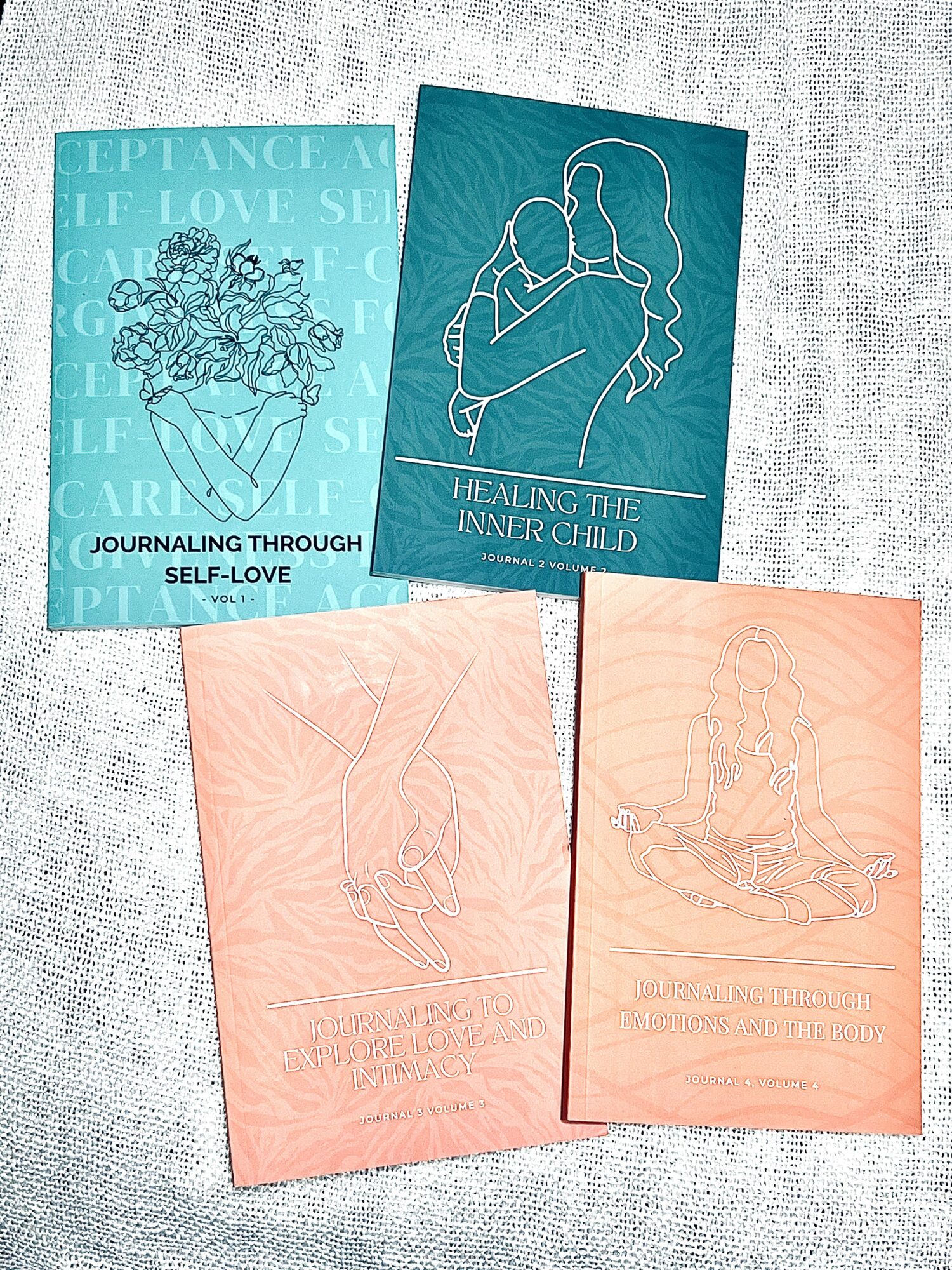 Four booklets with line art and text, two with teal backgrounds and two with peach backgrounds, arranged on a light surface.