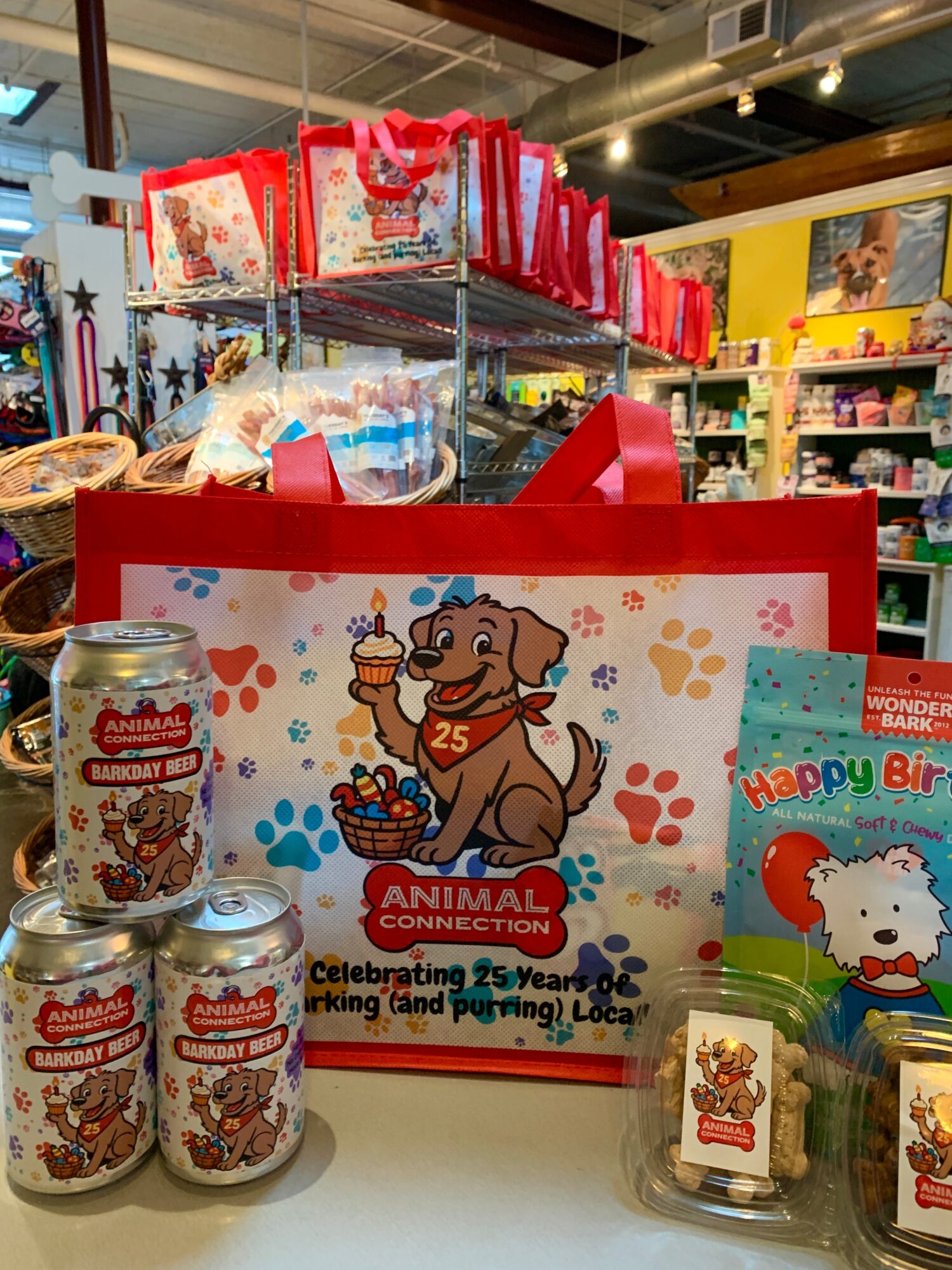 Birthday gift bag with a cartoon dog holding a cupcake, surrounded by paw prints, on a store counter with toys and gifts.