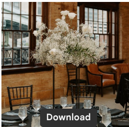 Large white floral centerpiece on a table in a room with wooden walls and large windows.