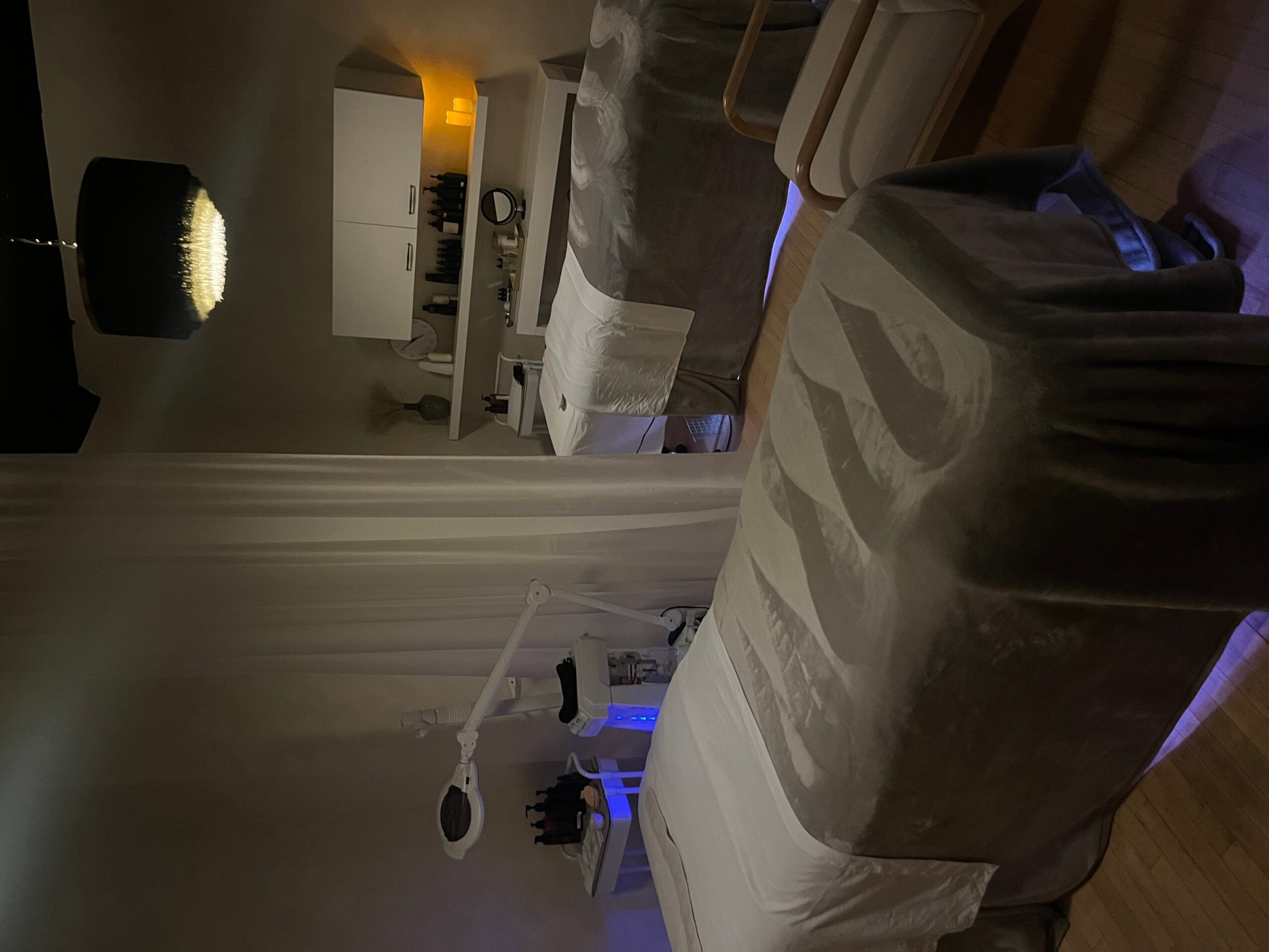 Living room with a bed, a lamp, and a kitchen area in the background, viewed from a tilted angle.