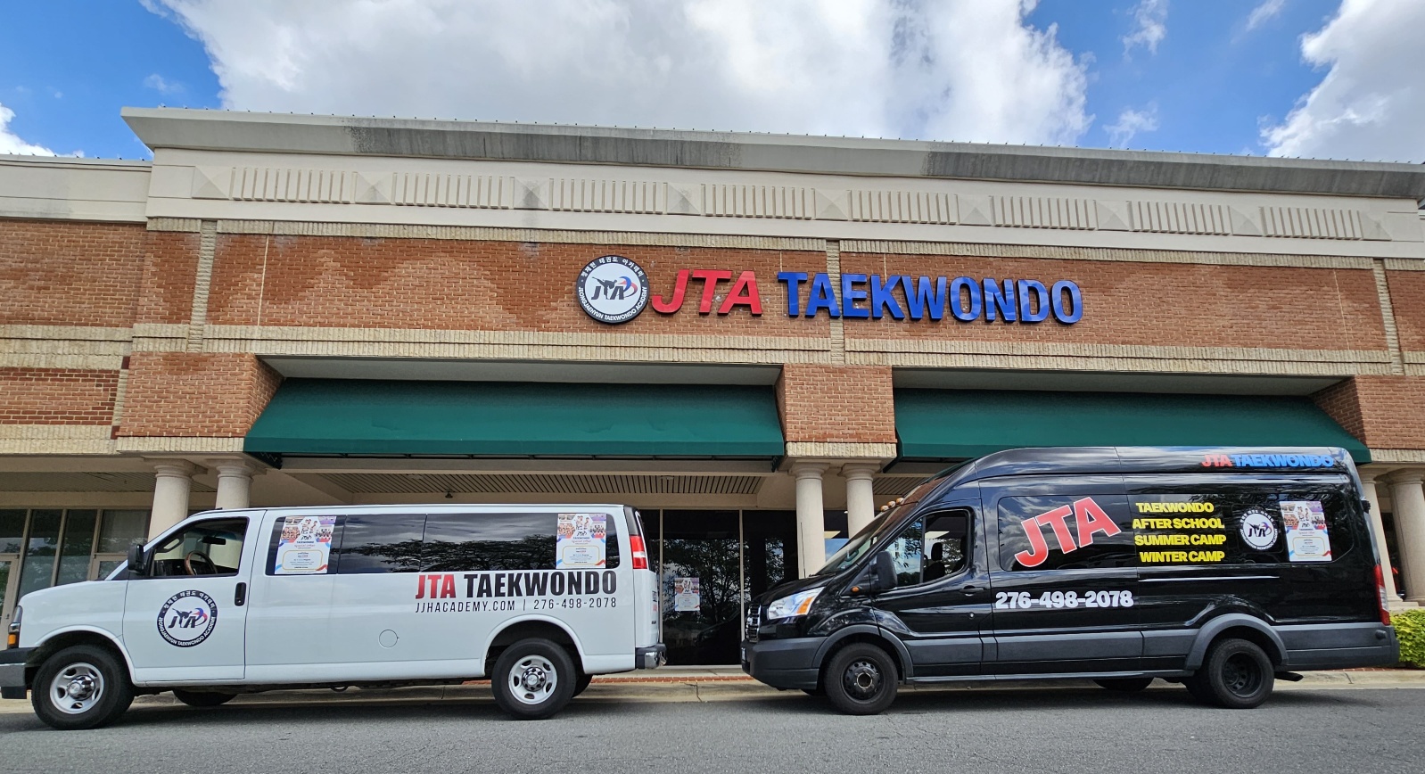 Two vehicles parked in front of a taekwondo school building, one white and one black, with the school's sign above.