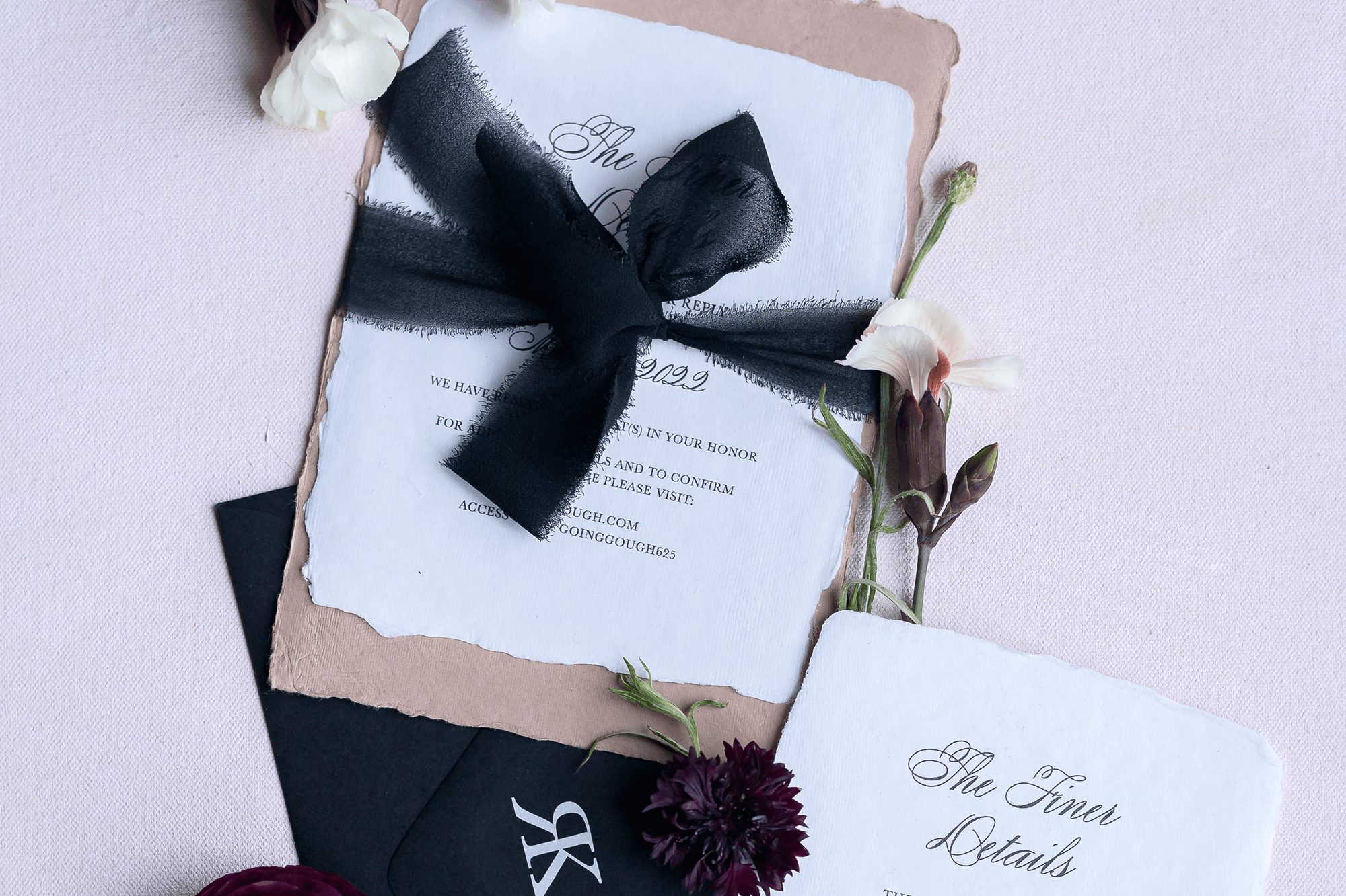 Invitation card with black ribbon, surrounded by flowers on a pink background.