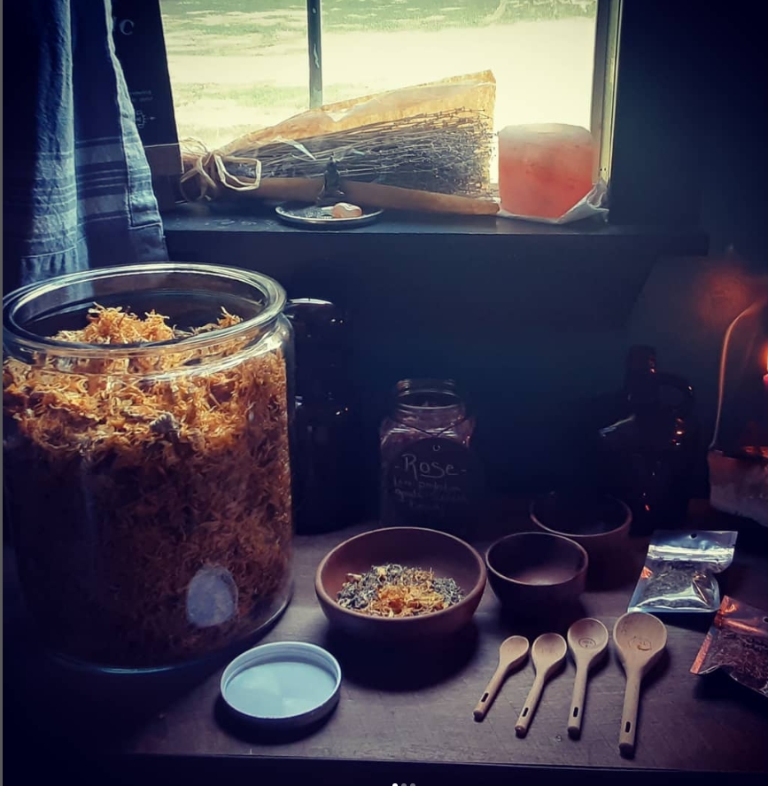Kitchen windowsill with jars, bowls, and spoons, sunlight streaming through window, view of outdoors, various kitchen items on surface.