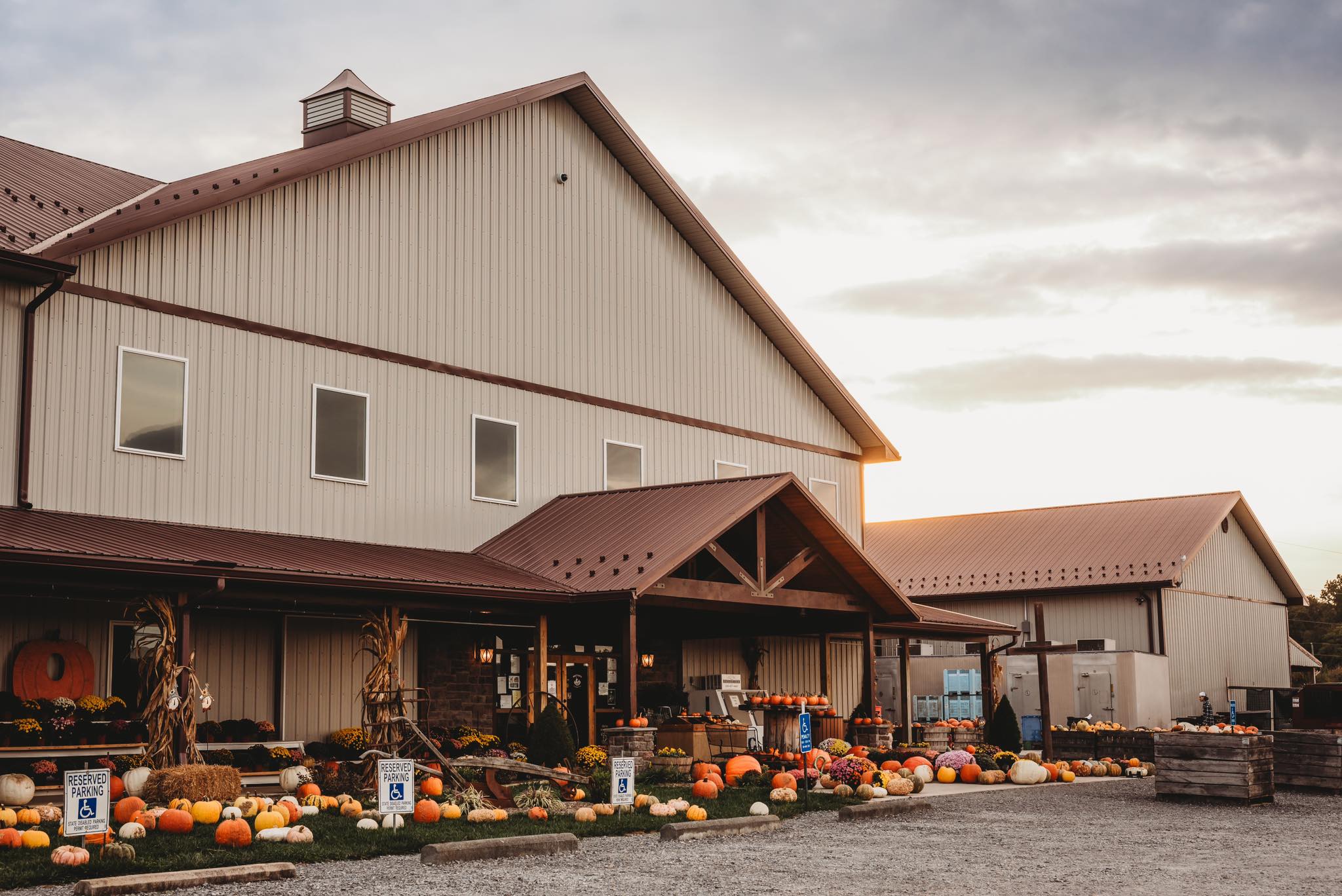 Farm store with pumpkins and fall decorations outside, under a cloudy sky.