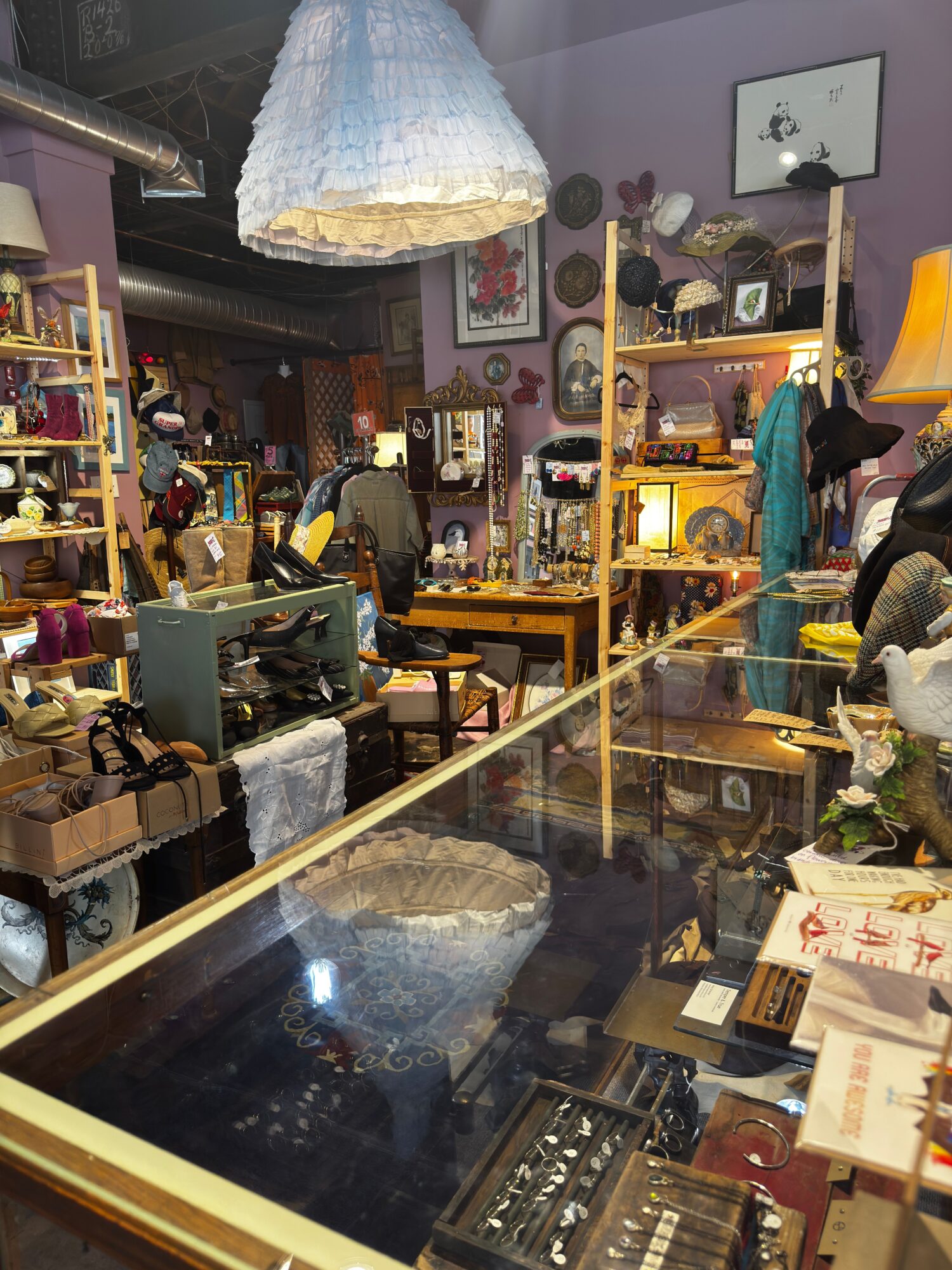 View of a store interior with shelves, display cases, and various items, seen through a glass window.