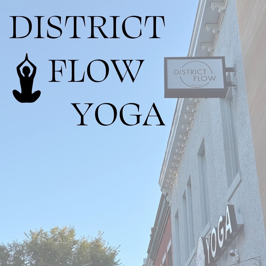 Sign for District Flow Yoga with a person in a yoga pose silhouette, building and sky in background.